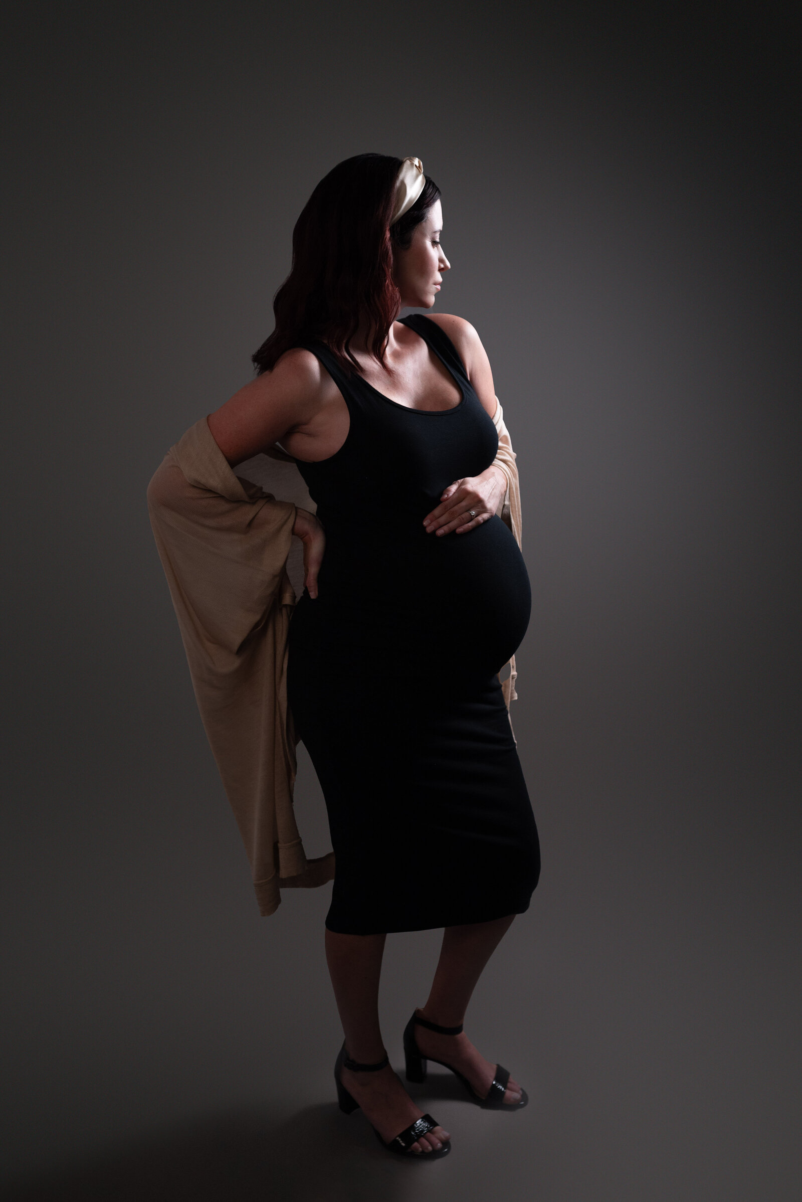 A pregnant woman poses with her hand on her stomach in her studio maternity pictures in Huntsville Alabama