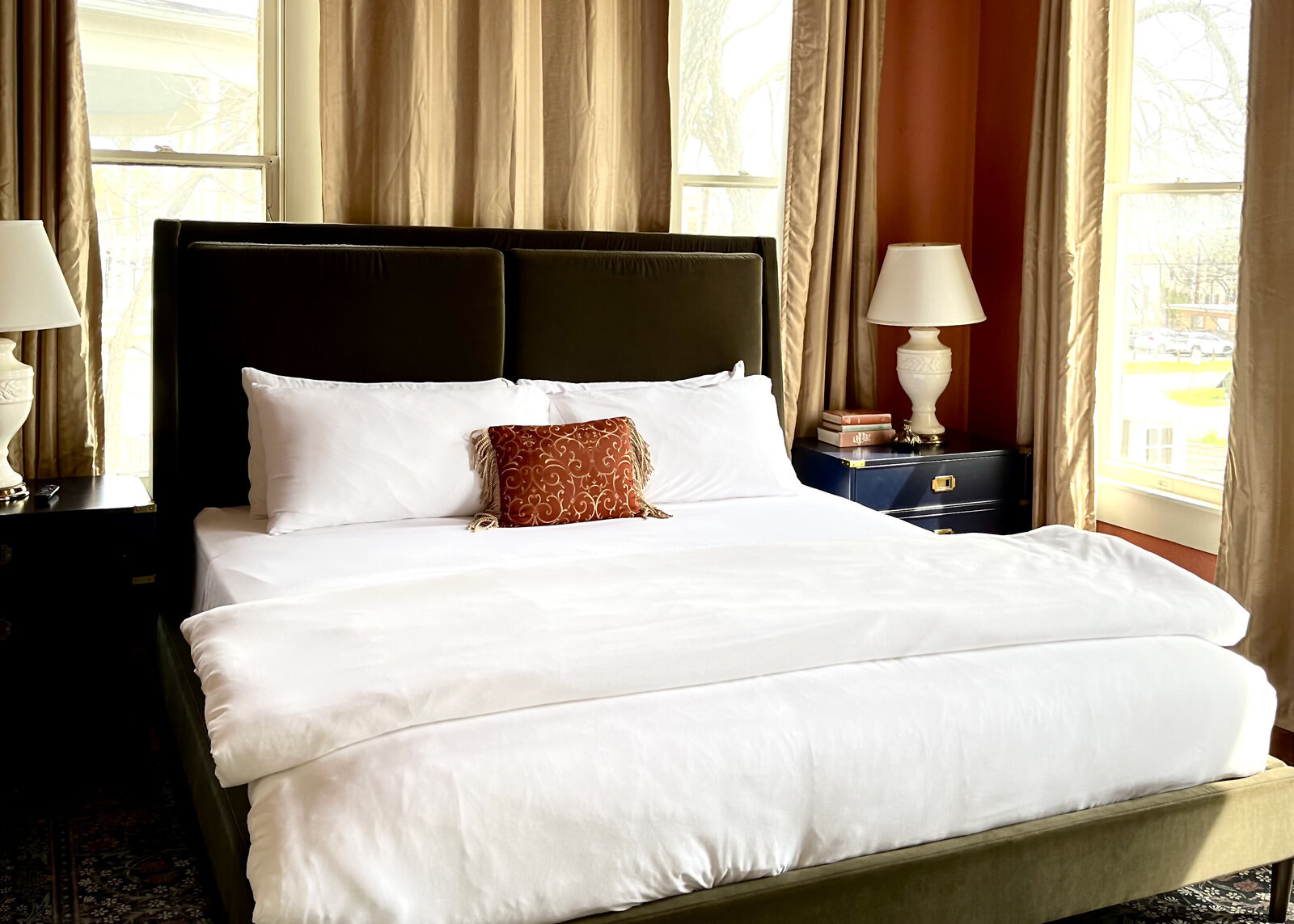 Green velCrisp white bedding sit atop a deep green velvet headboard complimenting a Morris & Co Ruggable in the Pedernales King room.vet headboard, white crisp bedding