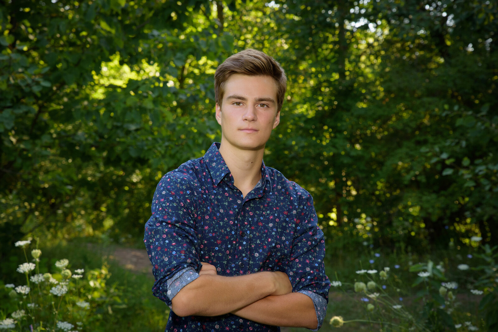 Senior boy wearing blue button down shirt crossing his arms at Fonferek Glen in Green Bay, Wisconsin