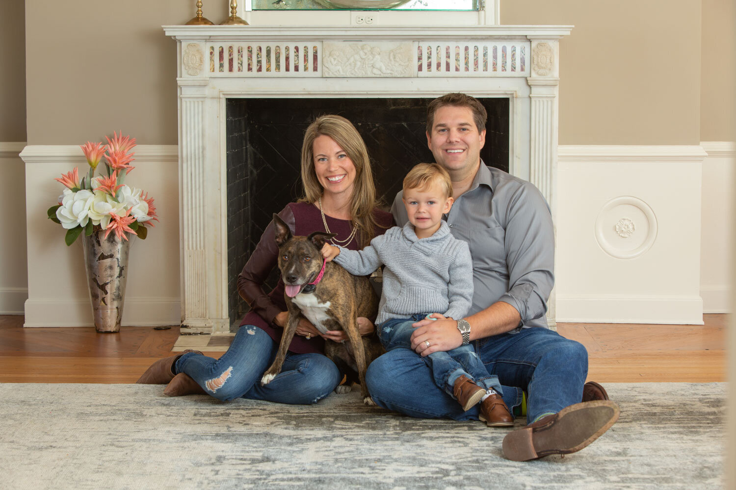 Family of three portrait with their puppy and the fire pit behind them