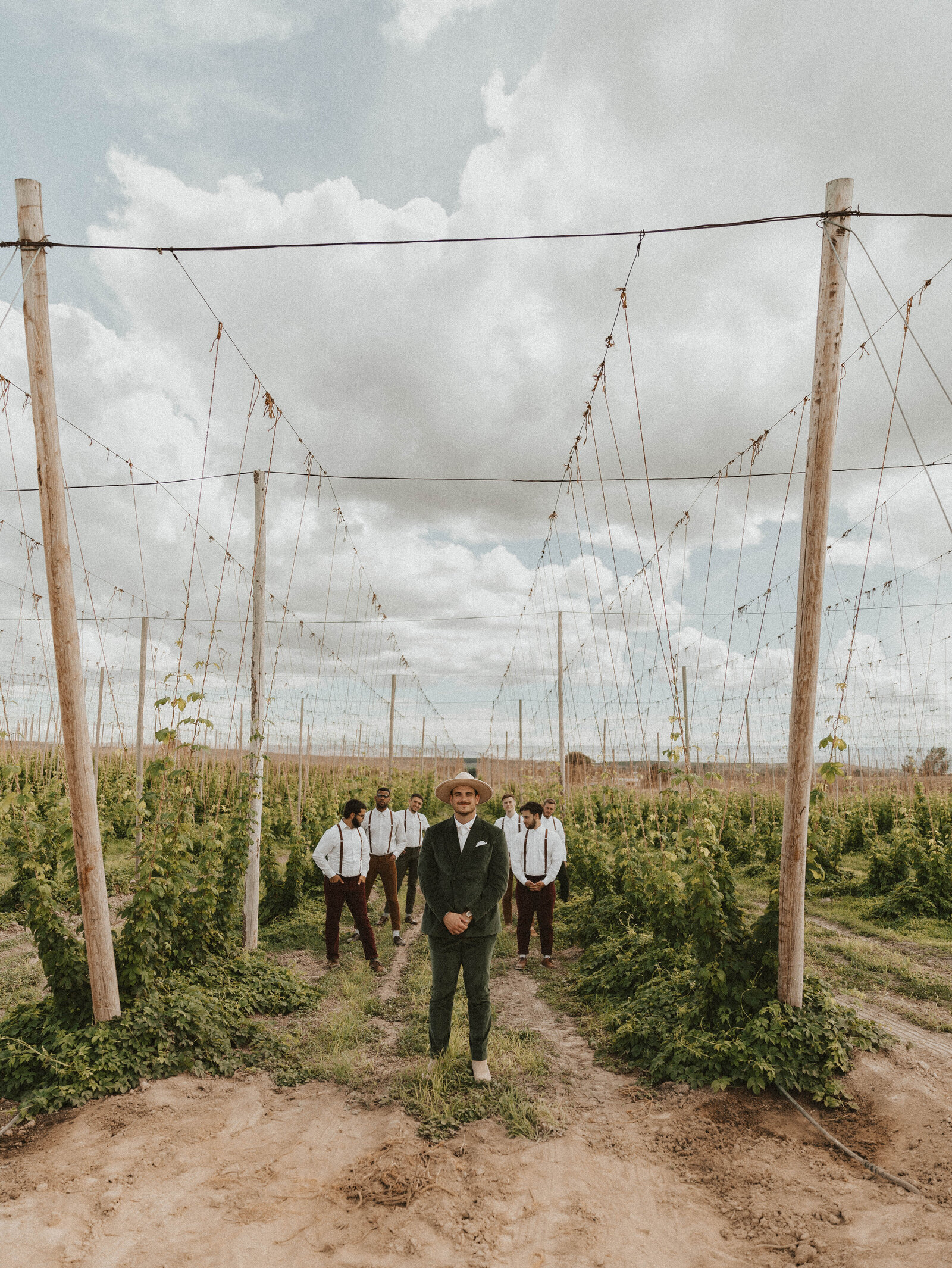 Groom stands with groomsmen in a hop field in Yakima, WA
