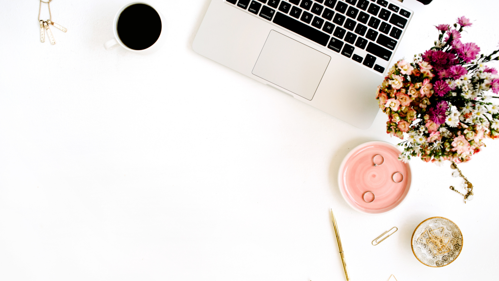 White desk with laptop, flowers, and jewelry dish