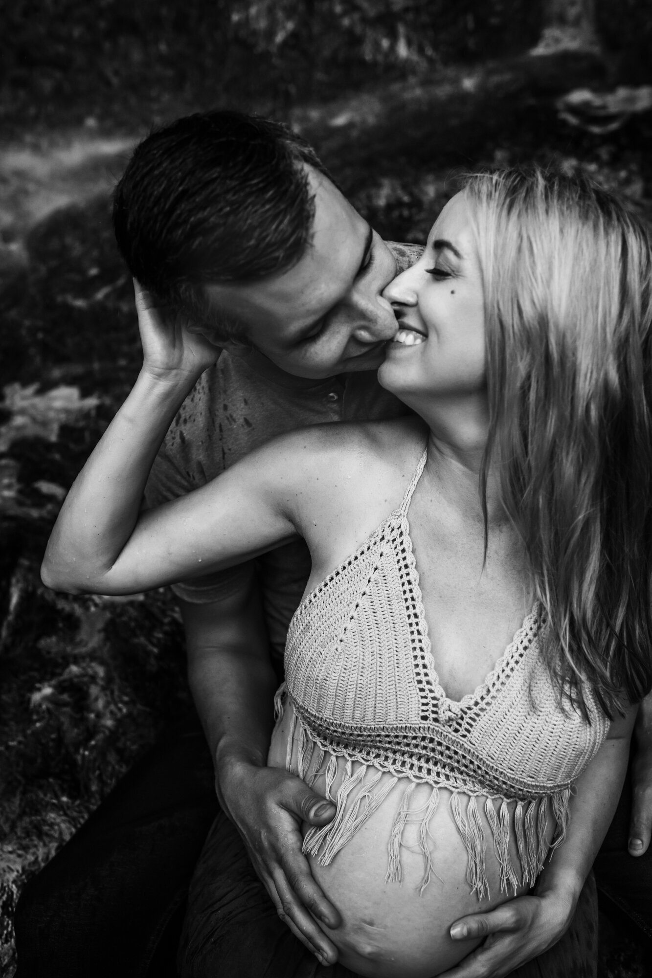 Maternity Photographer, a husband kisses his expectant wife as he holds her belly