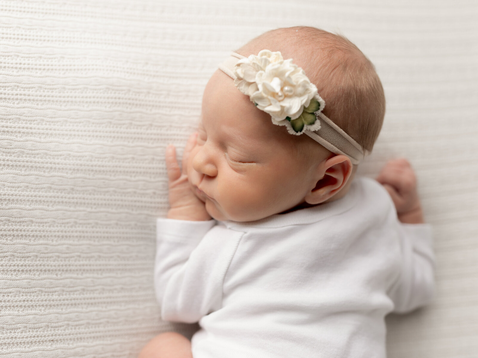 newborn baby girl in posed on white fabric for newborn studio photography