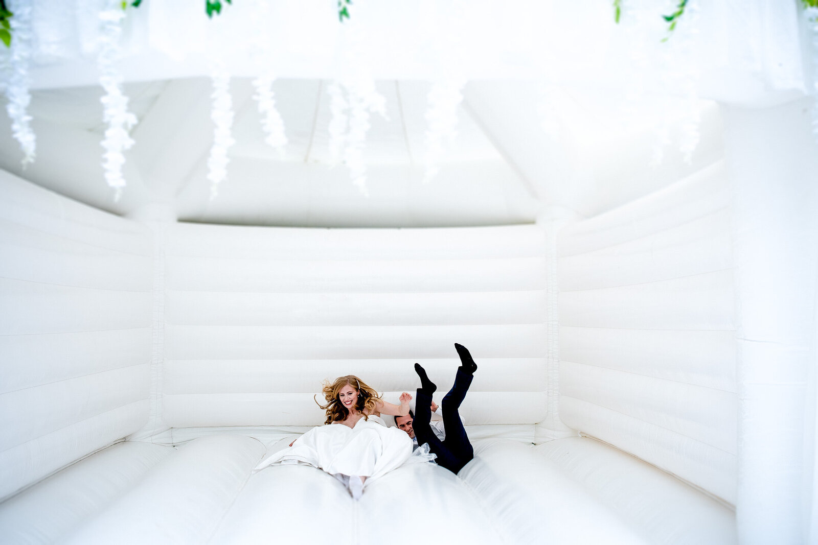 bride and groom on a white bouncy castle during their wedding in bristol