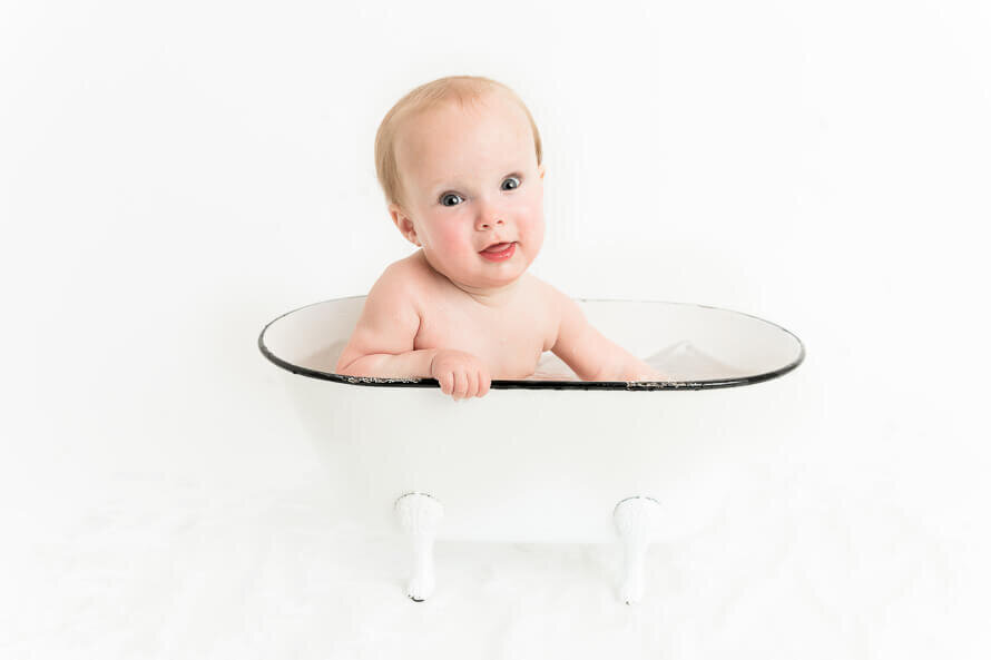 Baby in a tub looks at camera.
