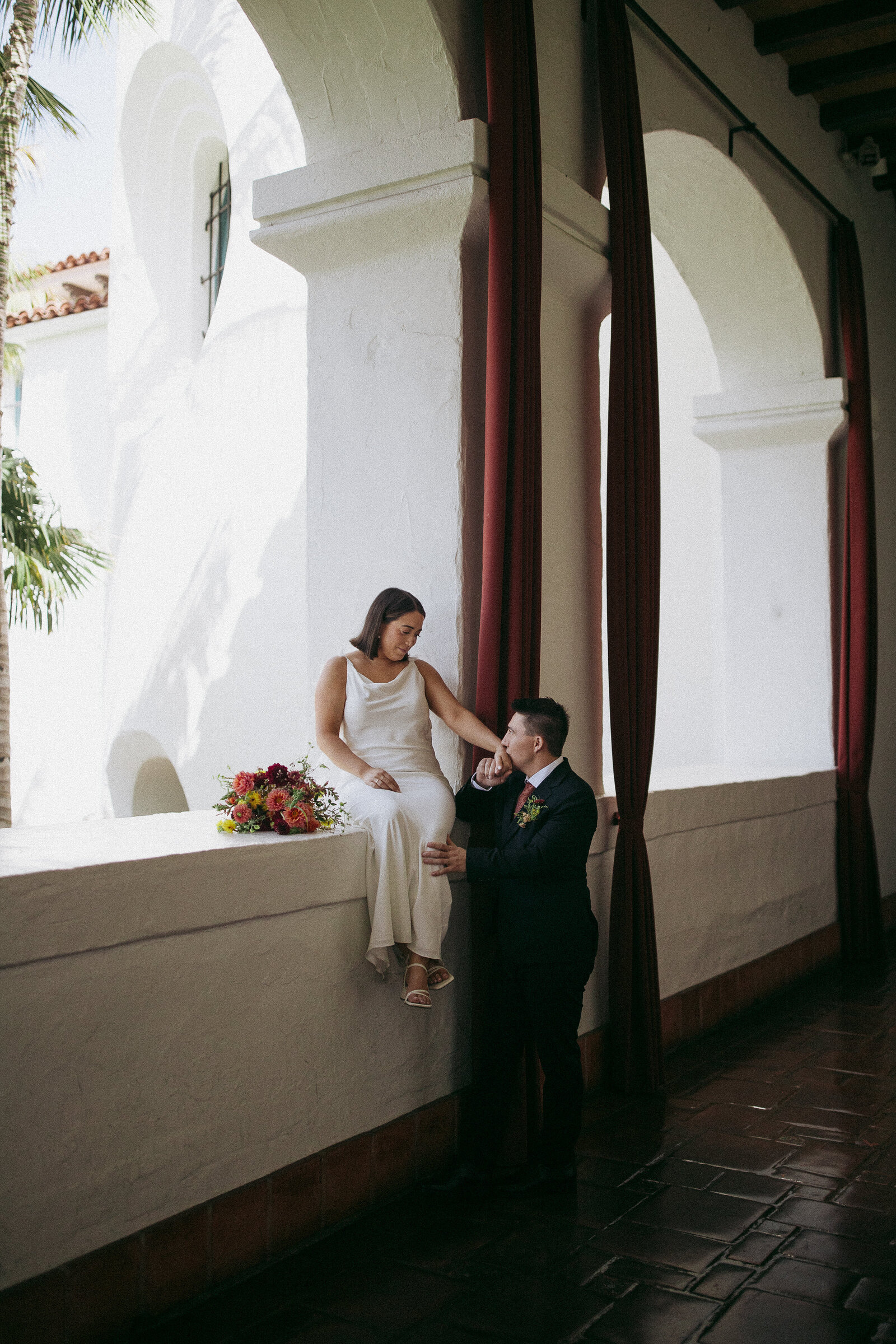 Groom kisses bride's hand during intimate moment at Santa Barbara Courthouse wedding