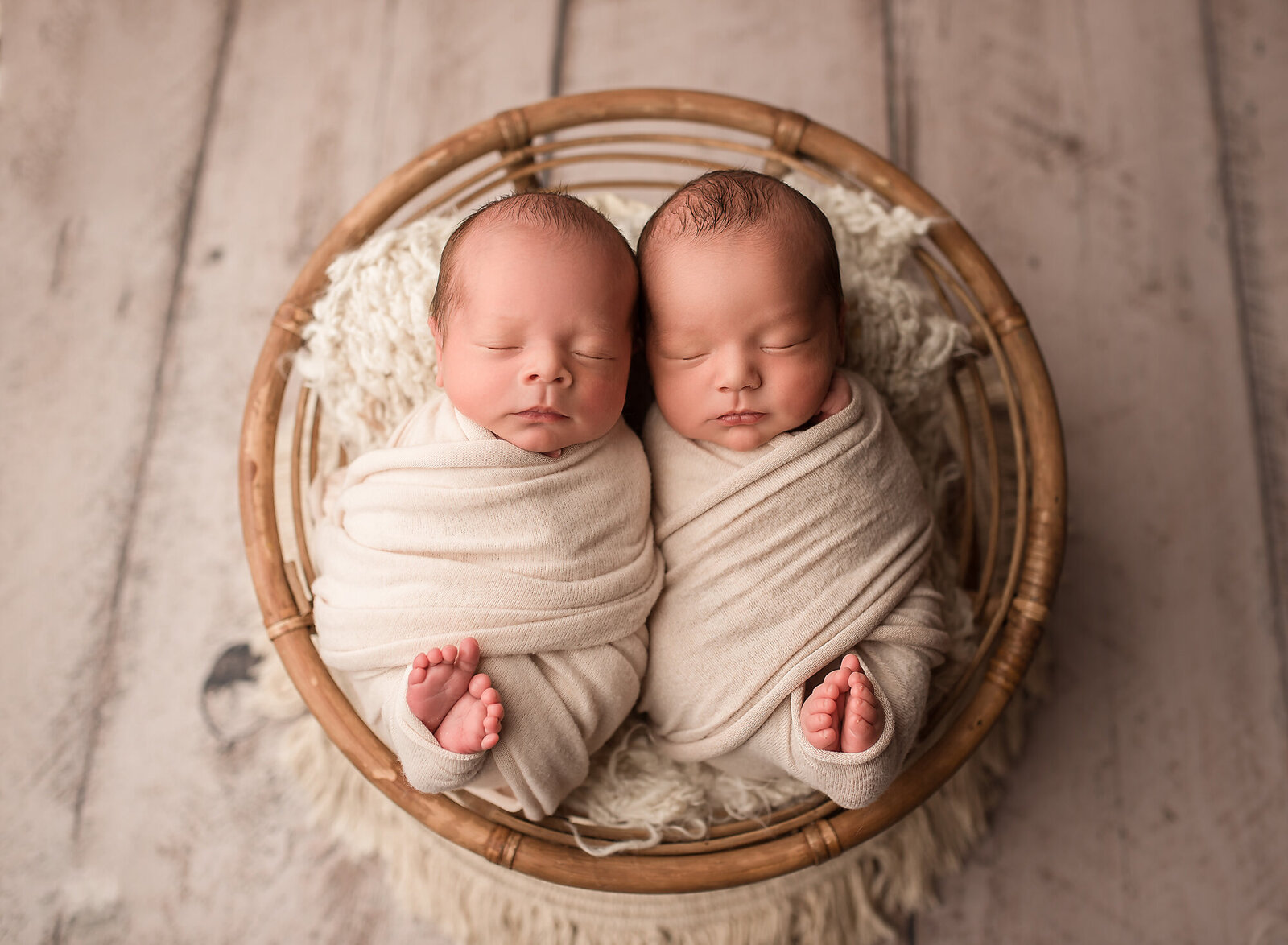twin newborn boys with neutral colors and toes pinking