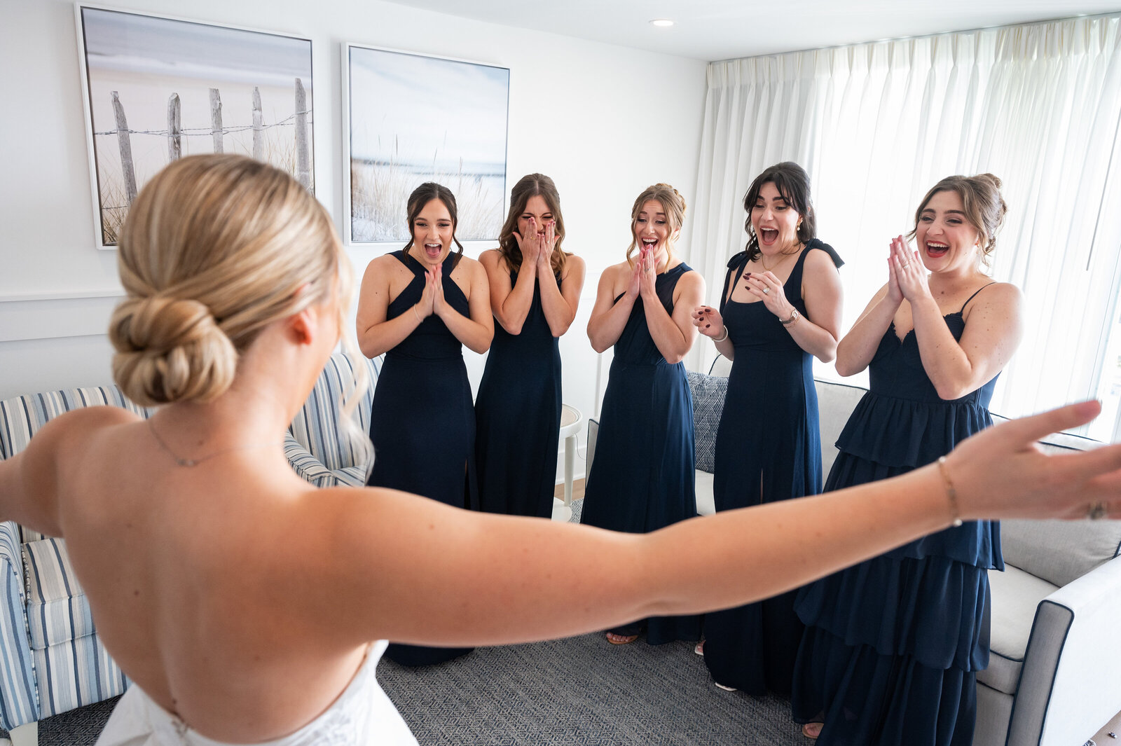 Bride showing her bridesmaids her dress.  Bridesmaids are wearing blue and are all surprised.