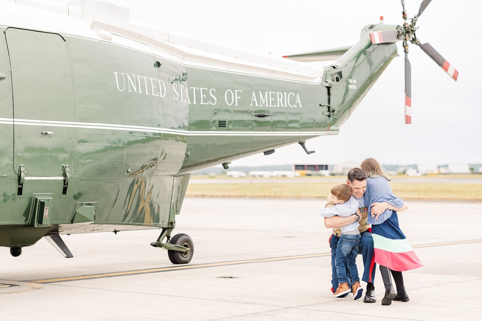 Kids running and hugging their dad in front of a Marine helicopter by Erin Thompson Photography