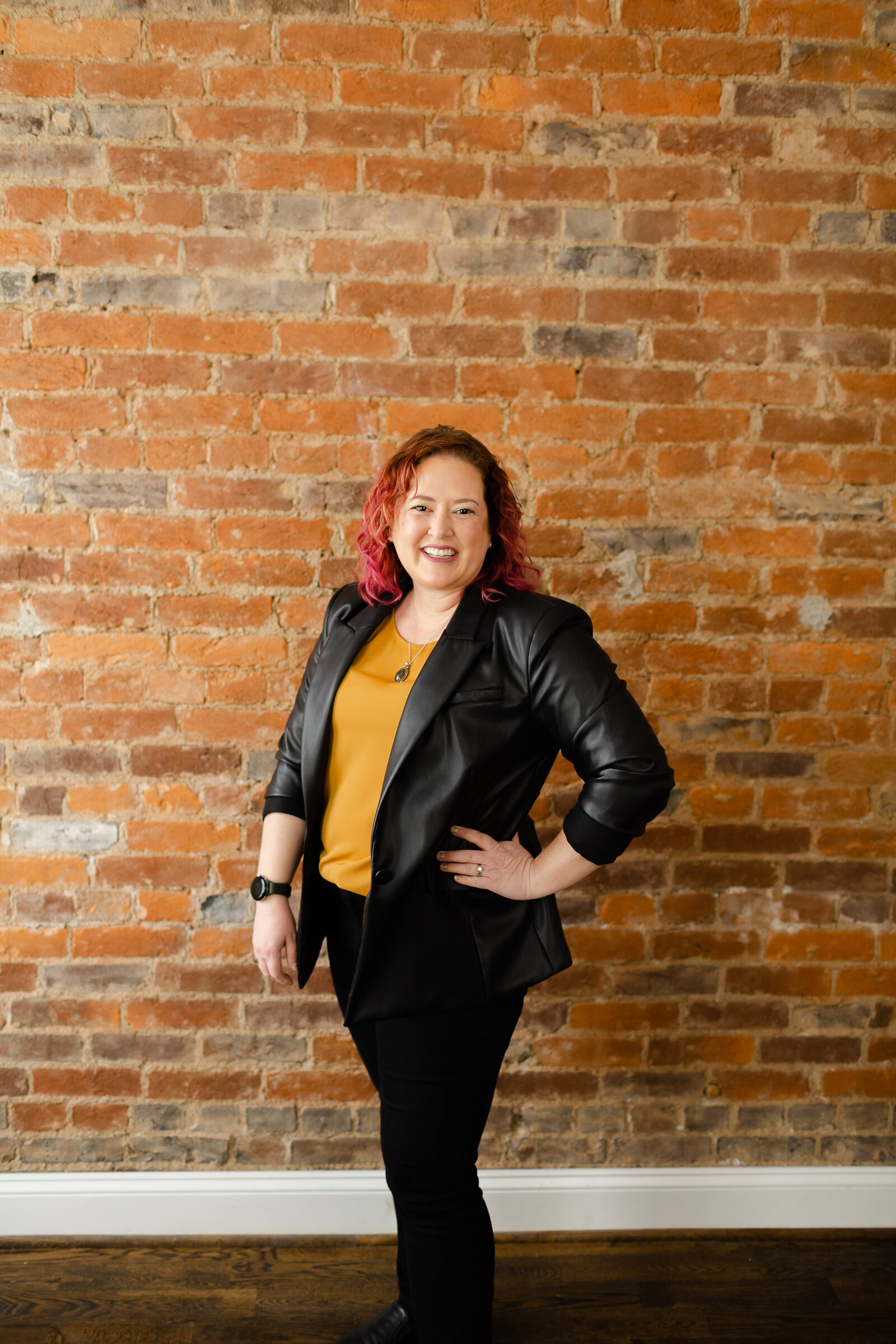 Color image of female business owner standing in front of brick