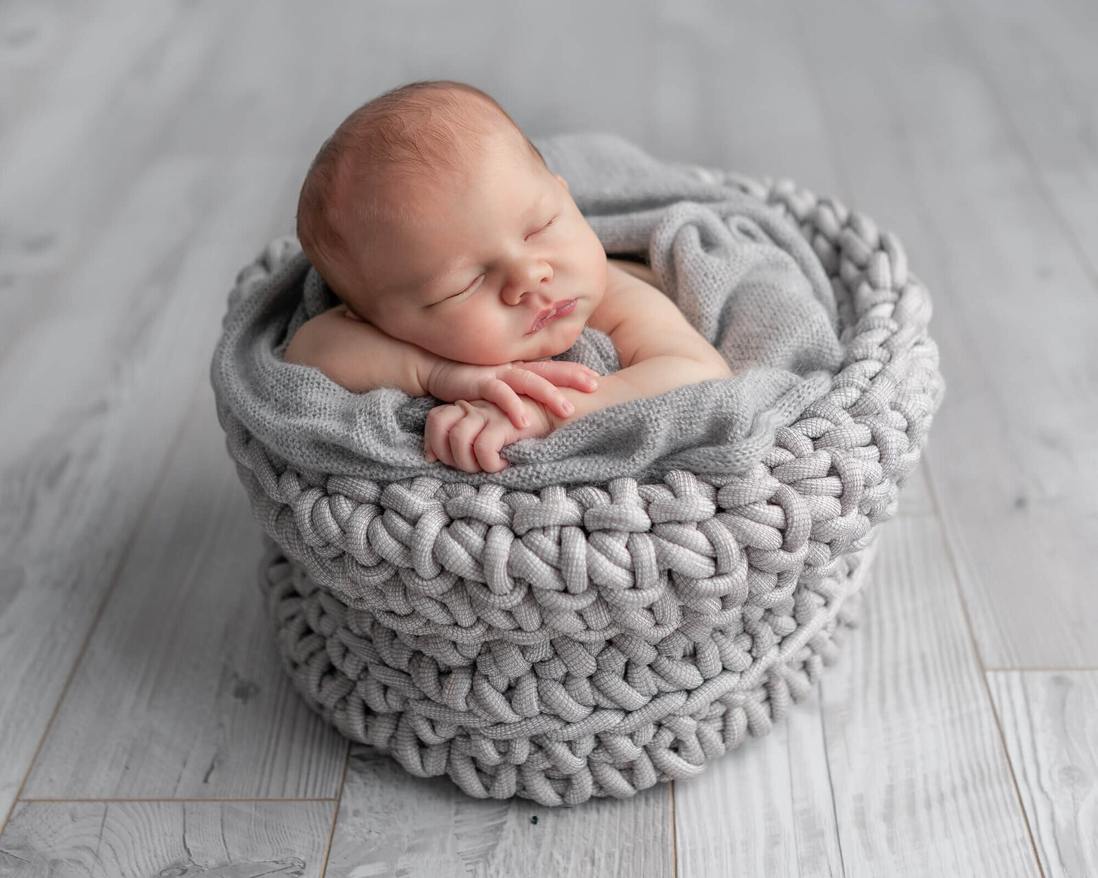 Newborn in a grey knit baasket