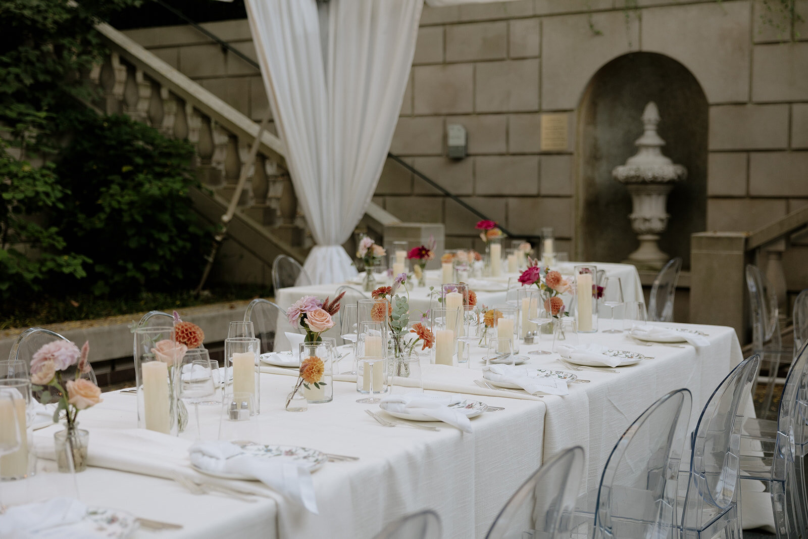 long dining table with white tablecloth and bud vases and candles