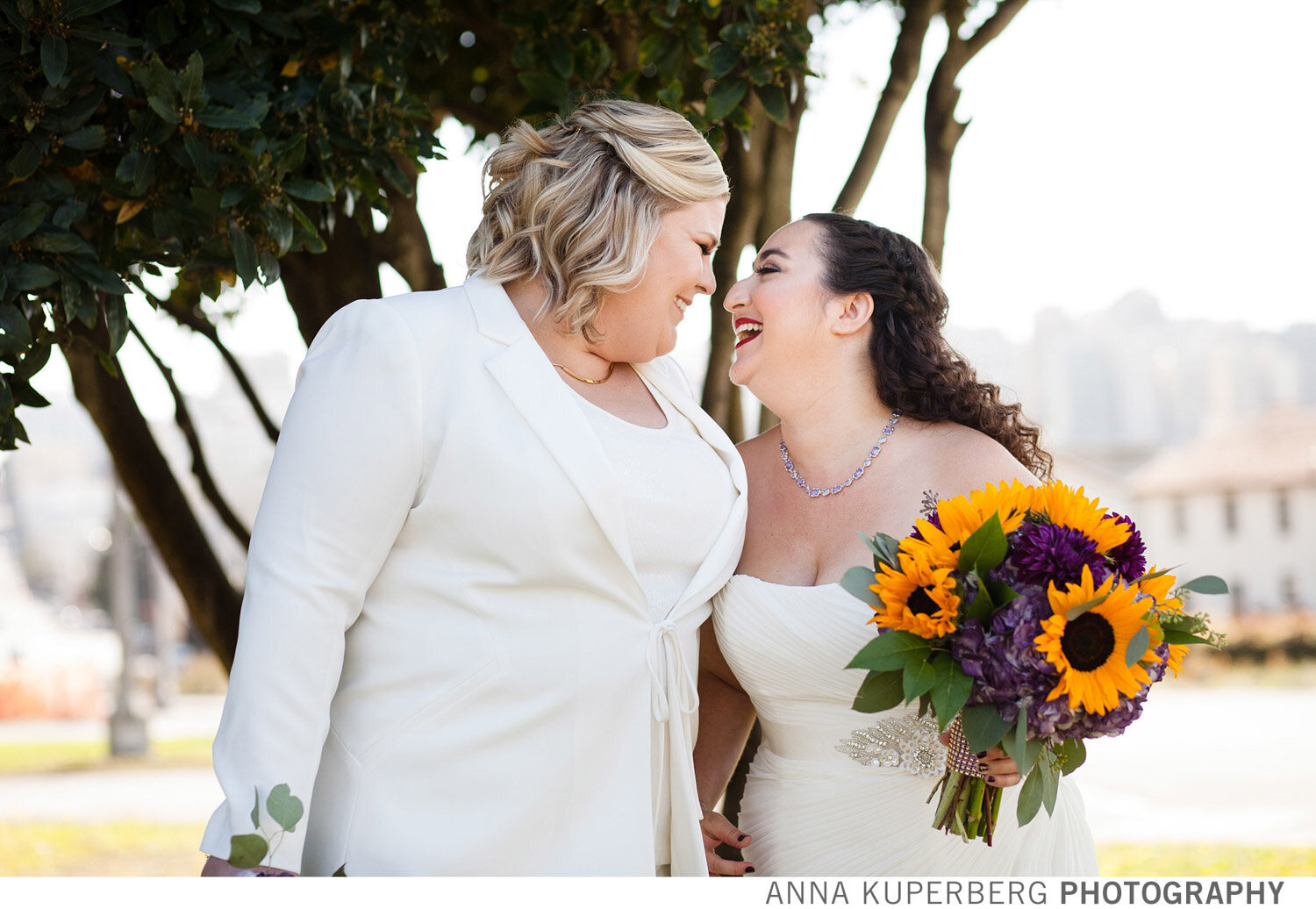Two brides smiling with sunflower wedding bouquet