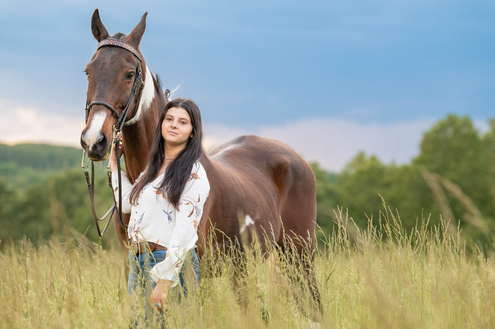 girl with horse in field looking at camera