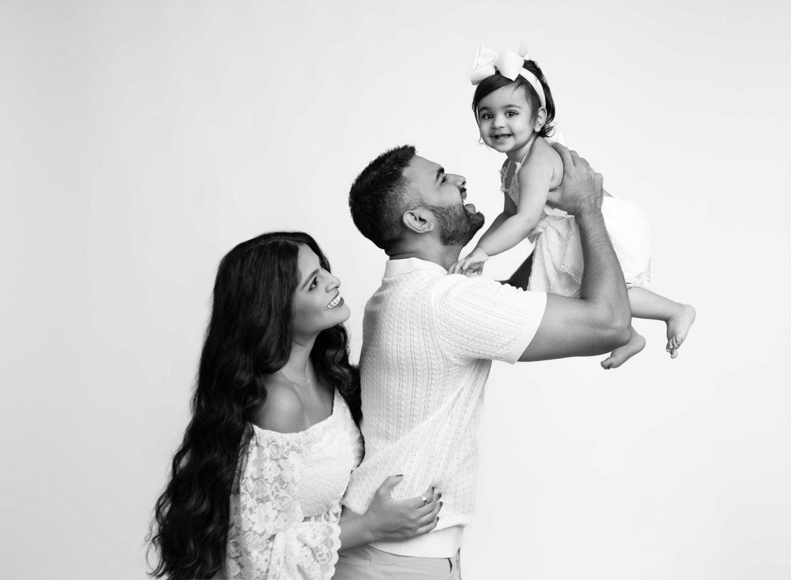 Dad tossing baby up in the air and Mom looking at her. 1st birthday photo taken by Jenni Nikki Photography in Atlanta, GA.