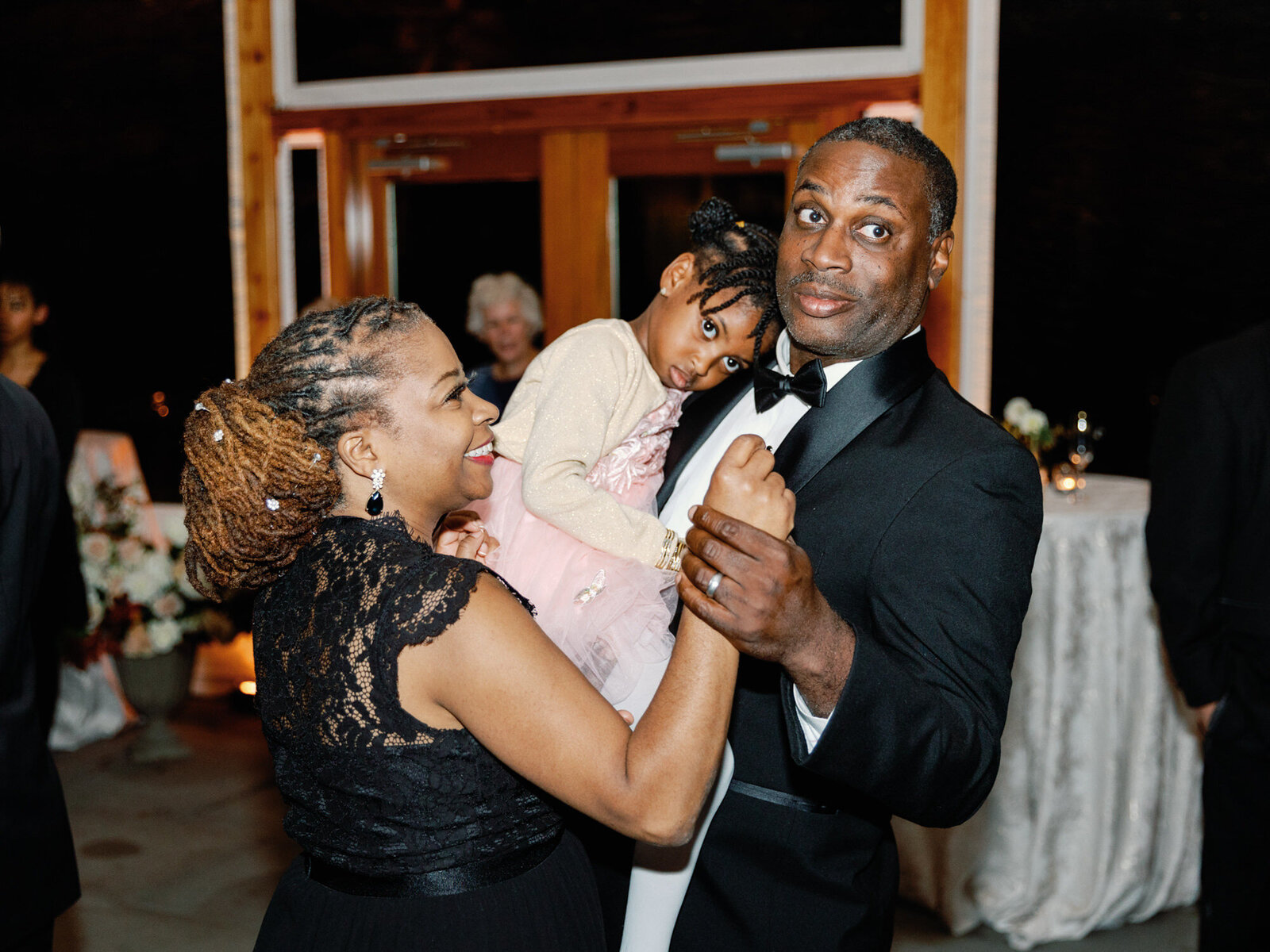 Family snuggles on the side of the dance floor at the wedding.