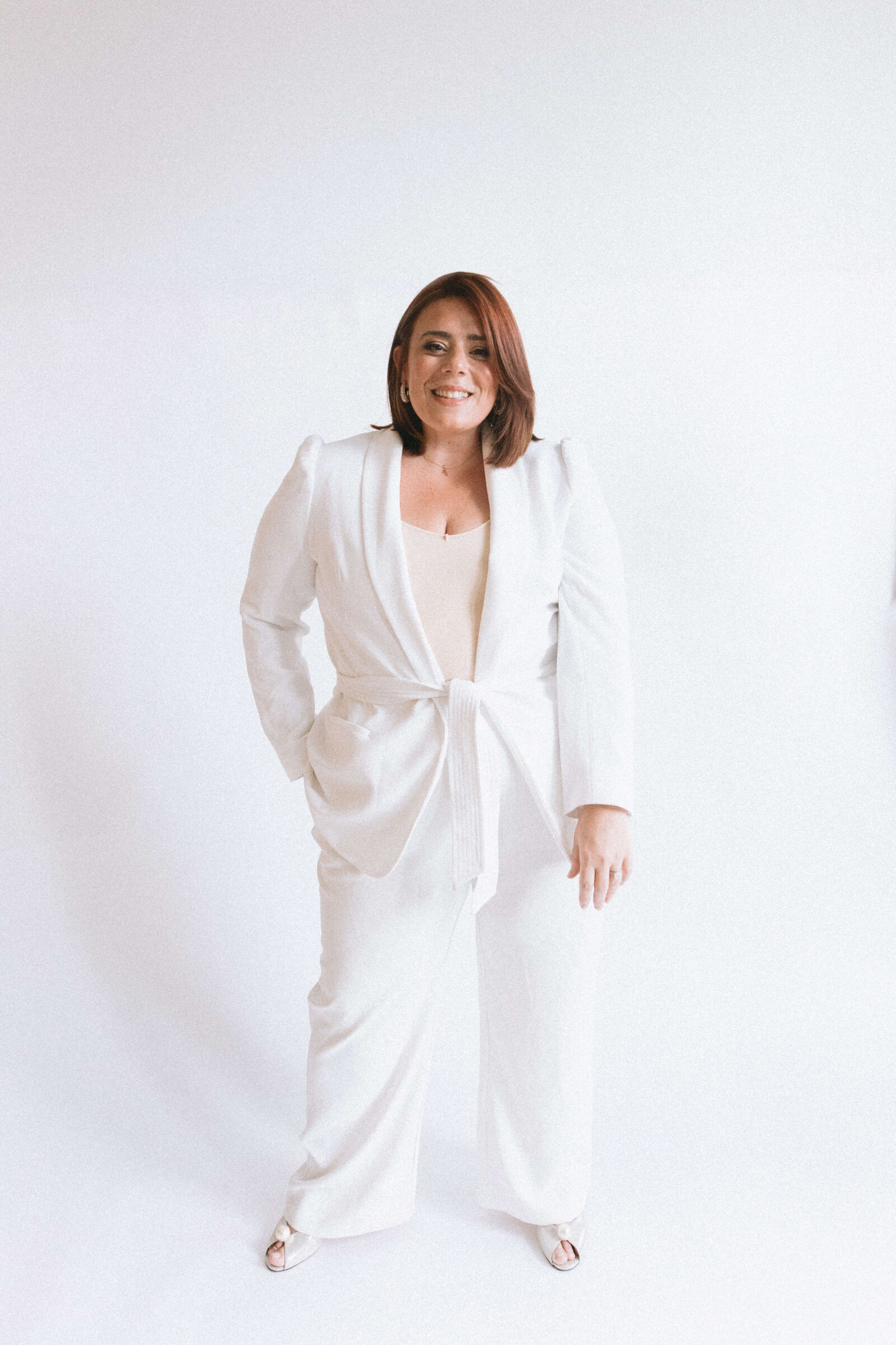 Casey, Founder of Most Valuable Bridesmaid smiling at the camera wearing white suit.