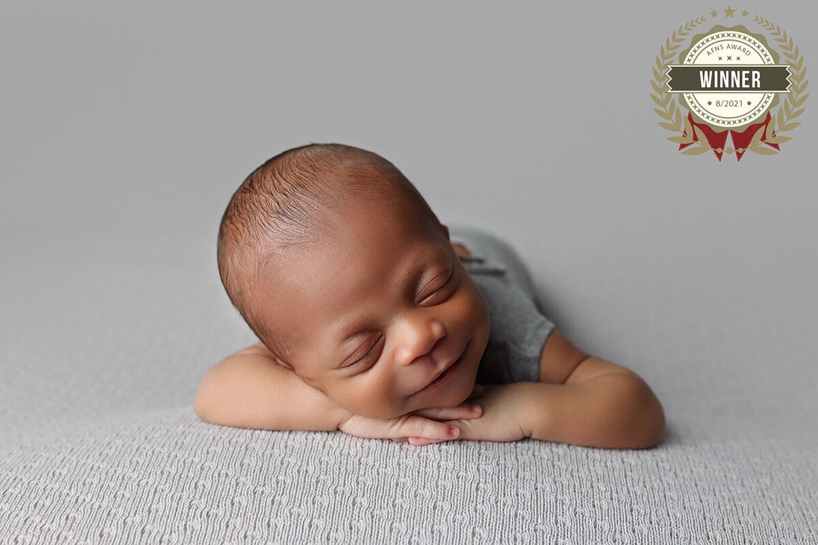 Sleeping baby in a cozy setup smiling at the camera