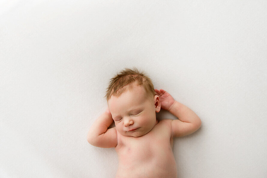 Sleepy baby on back in a photography studio.