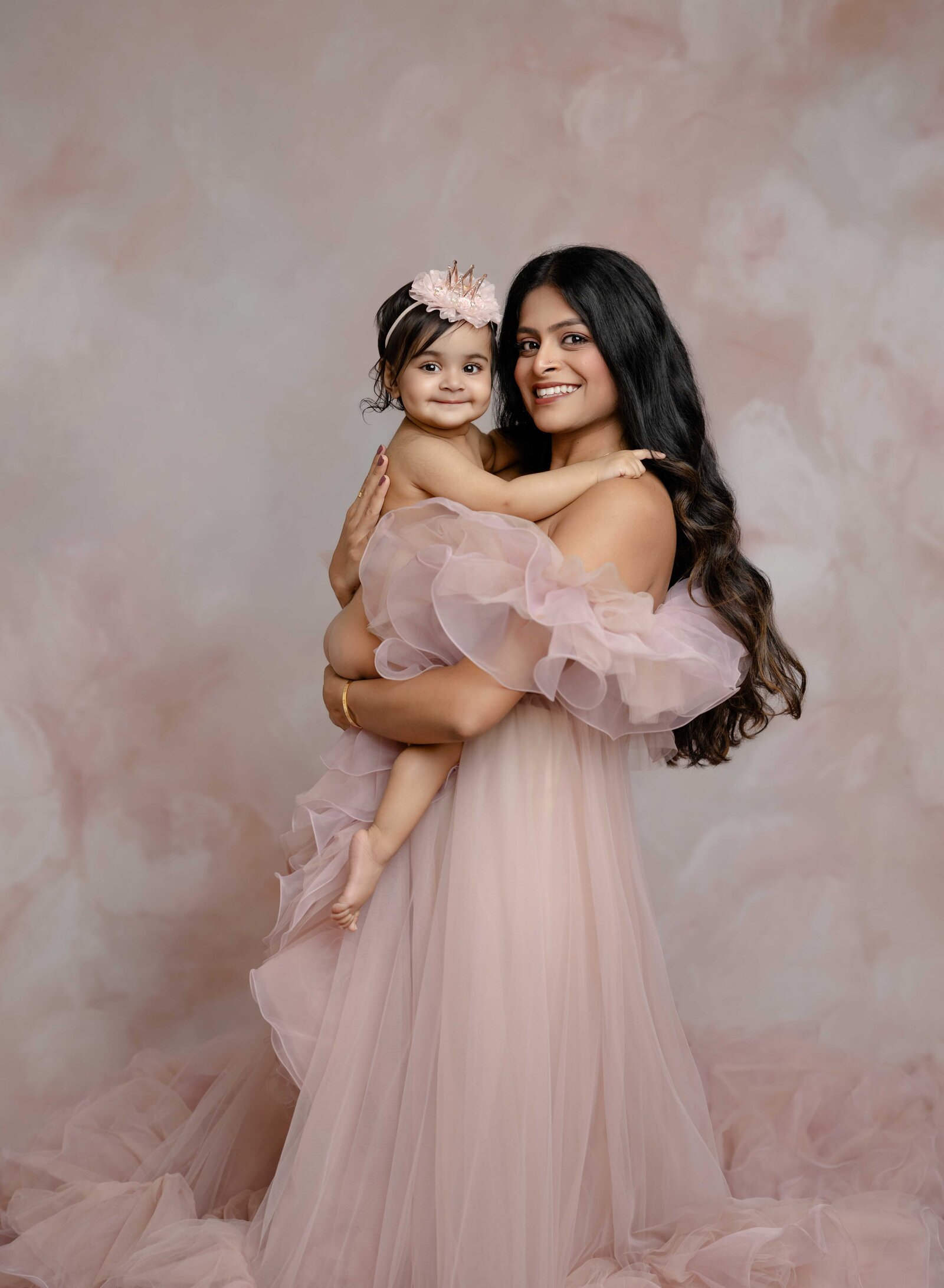 Mom and Baby in pink dresses, hugging and smiling at camera. Mommy and me photo taken by Jenni Nikki Photography in Atlanta, GA.