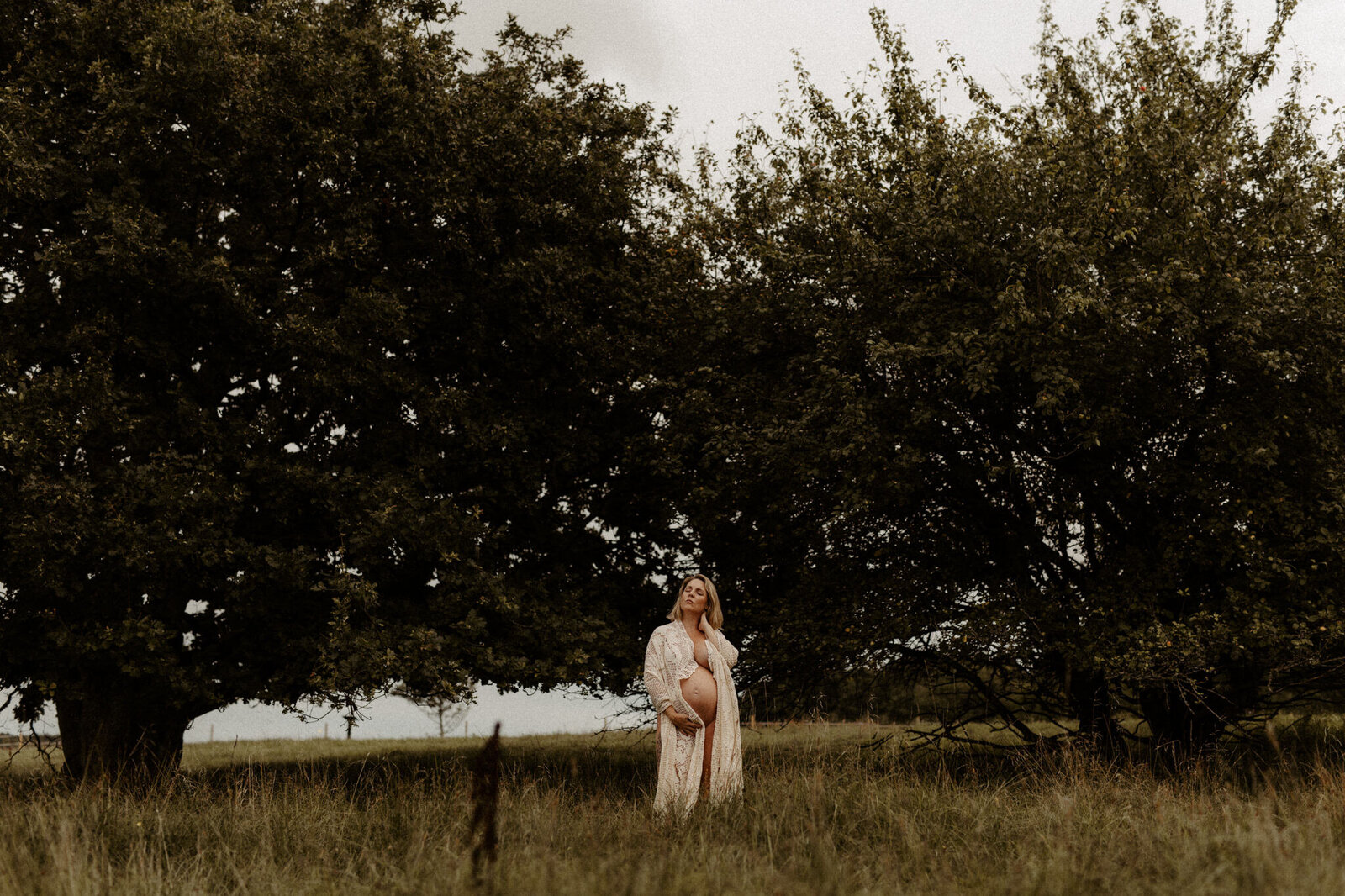 en gravid mamma insvept en virkad filt kramar om sig sig själv på ett fält