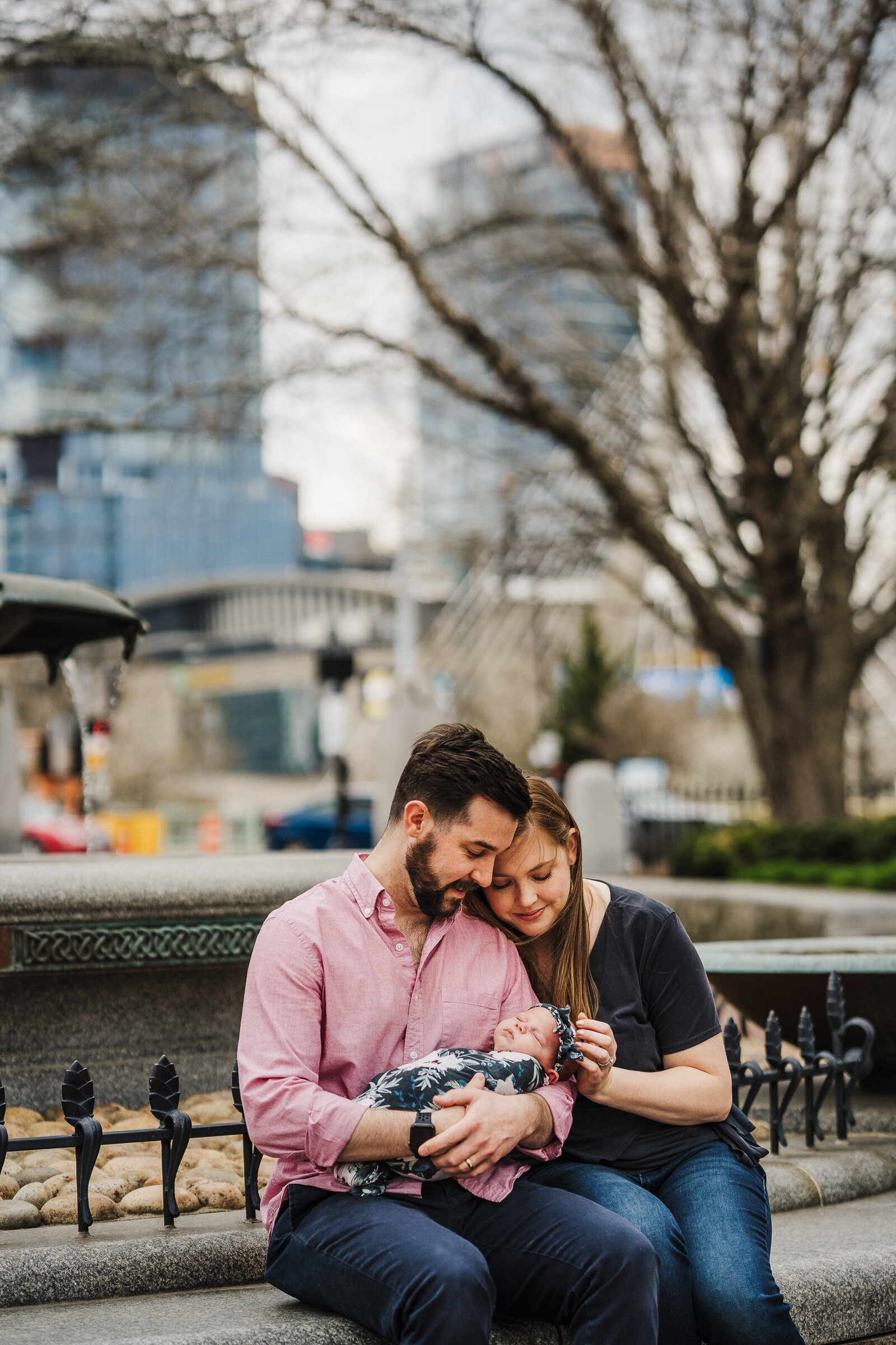 parents sit on side of fountain with new baby in charlestown