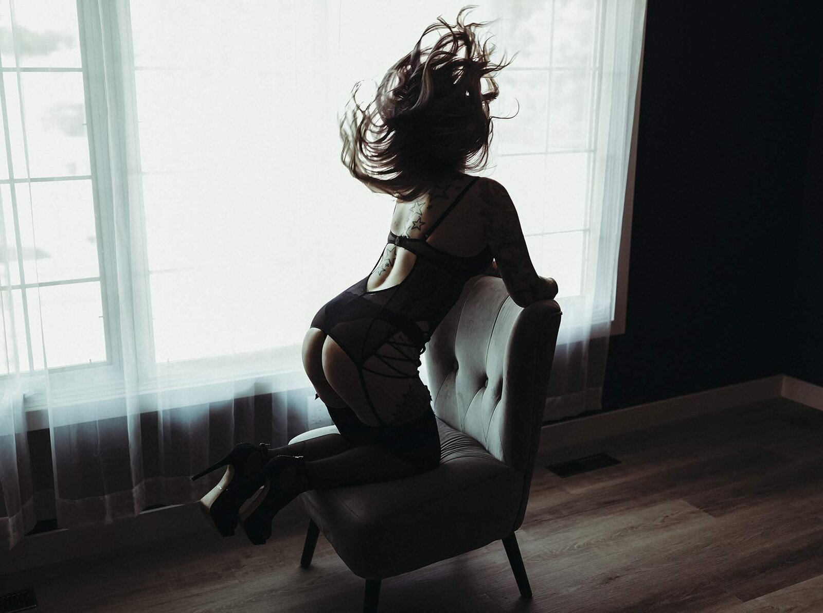 Woman whipping hair backwards on chair for boudoir photoshoot