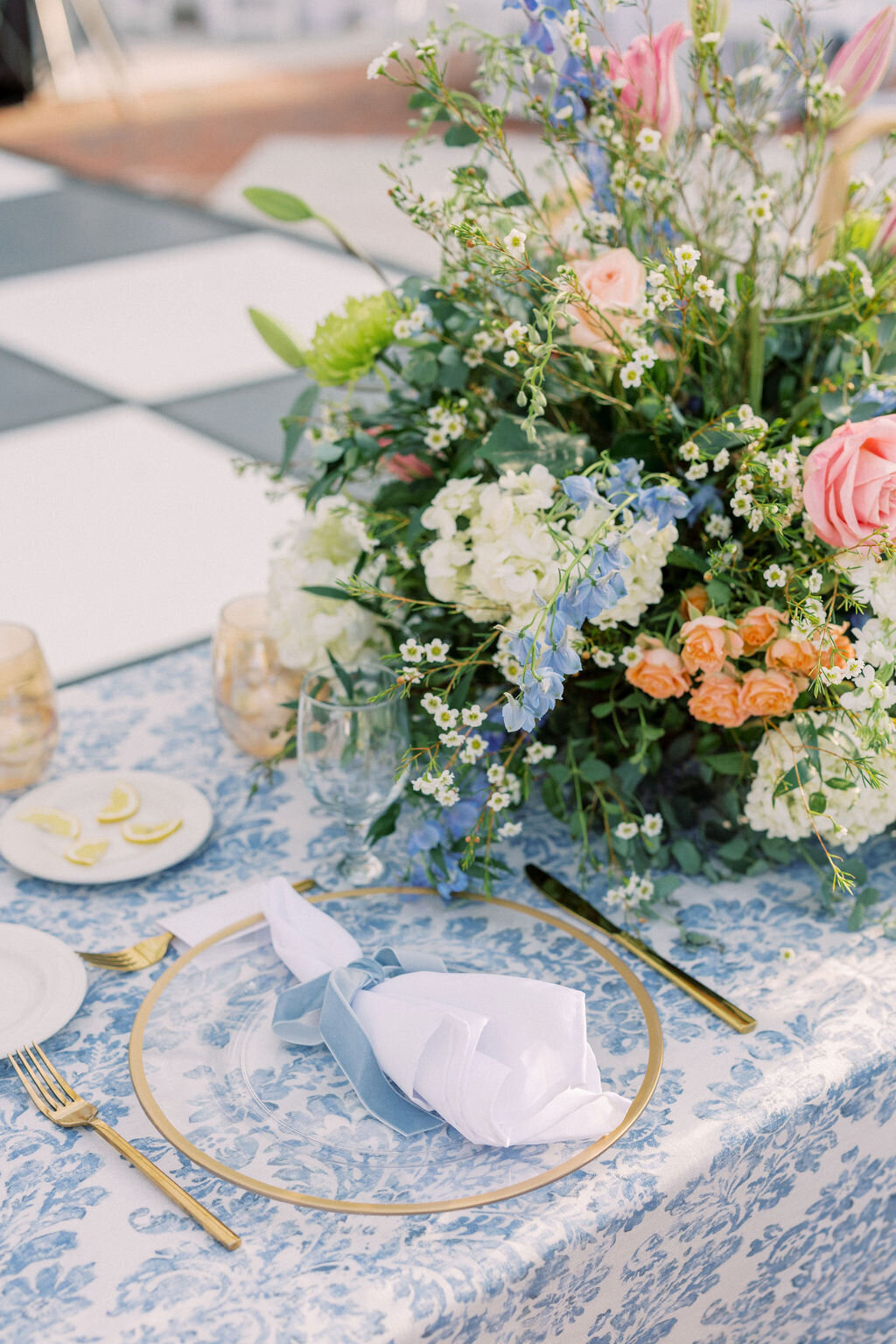 Blue toile tablecloth with pink and orange flowers and gold plates