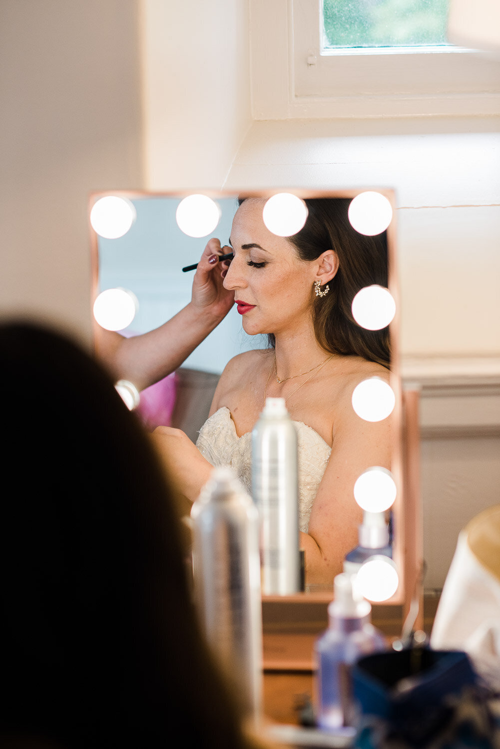 reflection of bride in vanity mirror getting makeup done