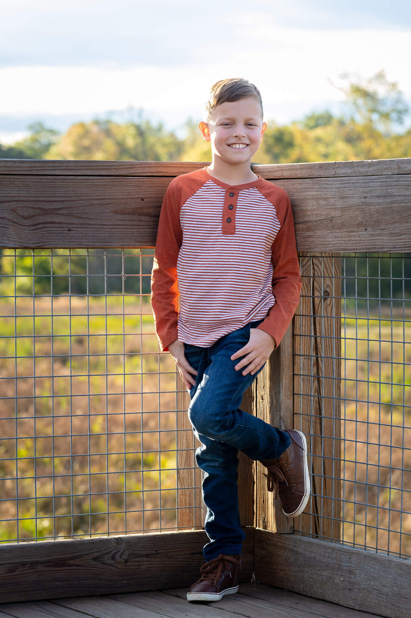 A boy posing against a fence.
