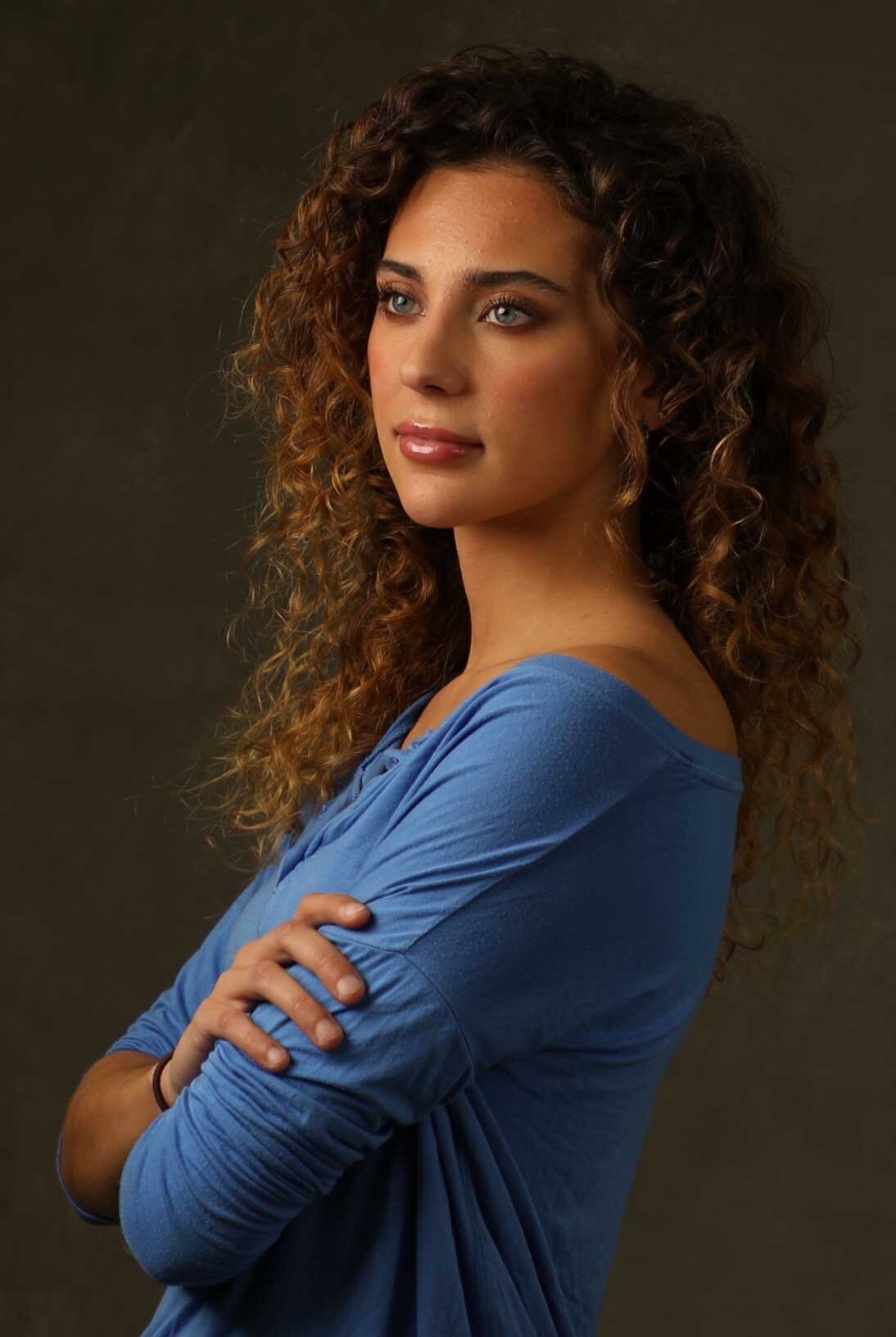 Curly haired woman crossing arms and smiling