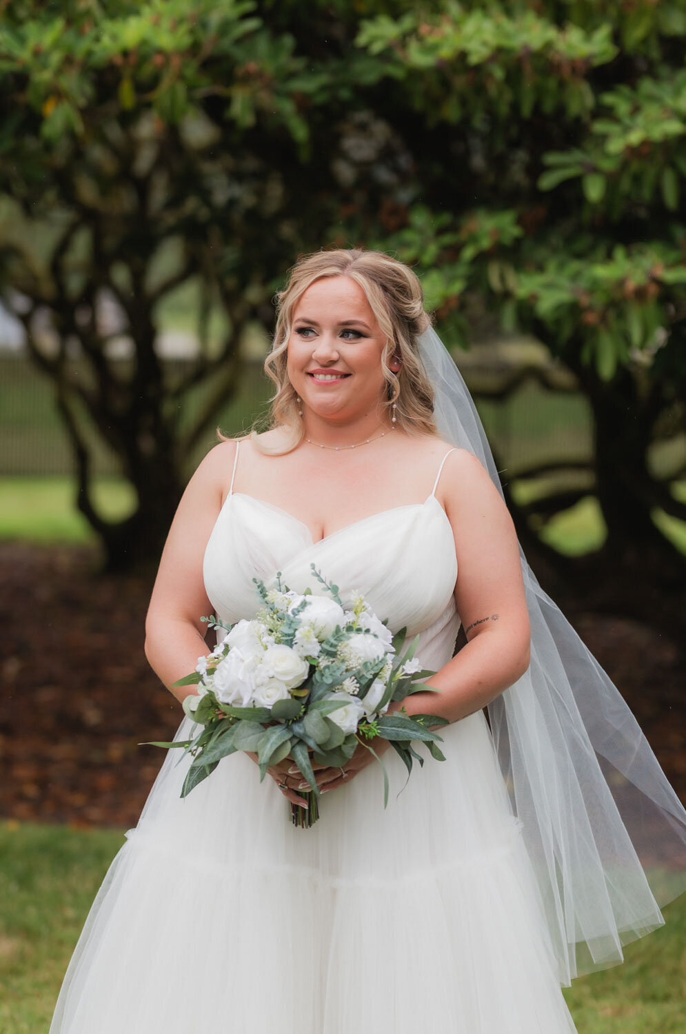 A bride holding a bouquet, standing gracefully in a lush garden