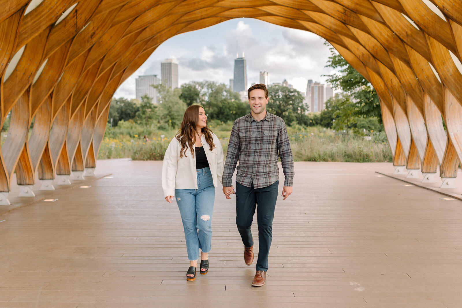 Young couple walking together while holding hands under the honeycomb sculpture in Chicago