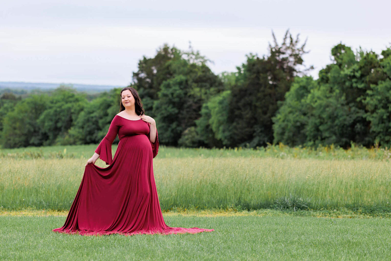 A woman in a red dress posing for her Manassas maternity portrait session.