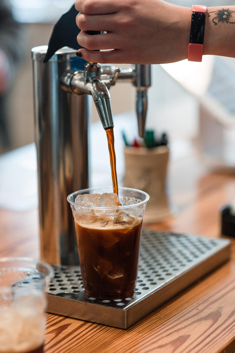 coffee being poured from a tap into a cup of ice