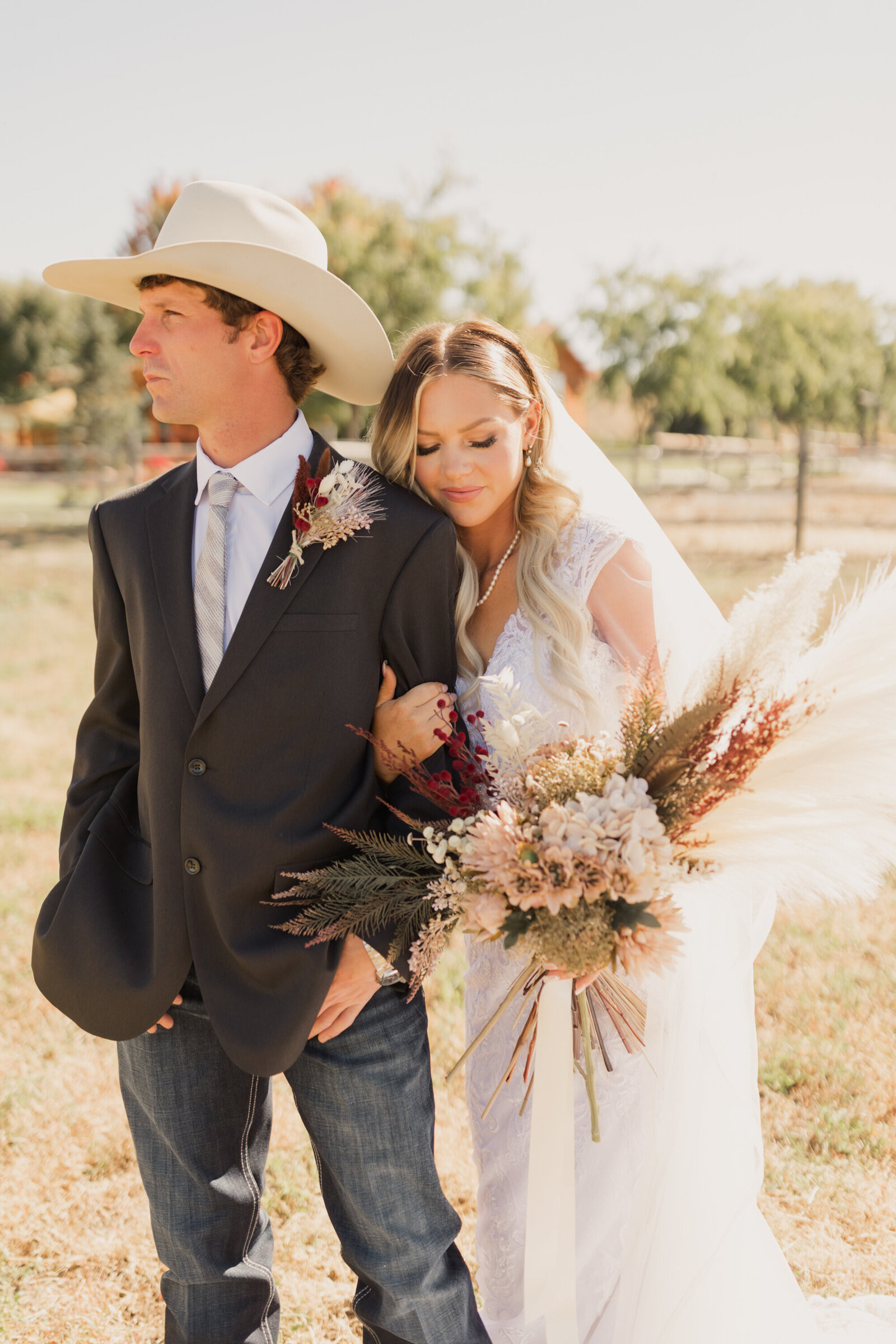 Bride holding a beautiful bouquet next to groom wearing a cowboy hat taken by Robin who is a Utah wedding photographer and a western wedding photographer
