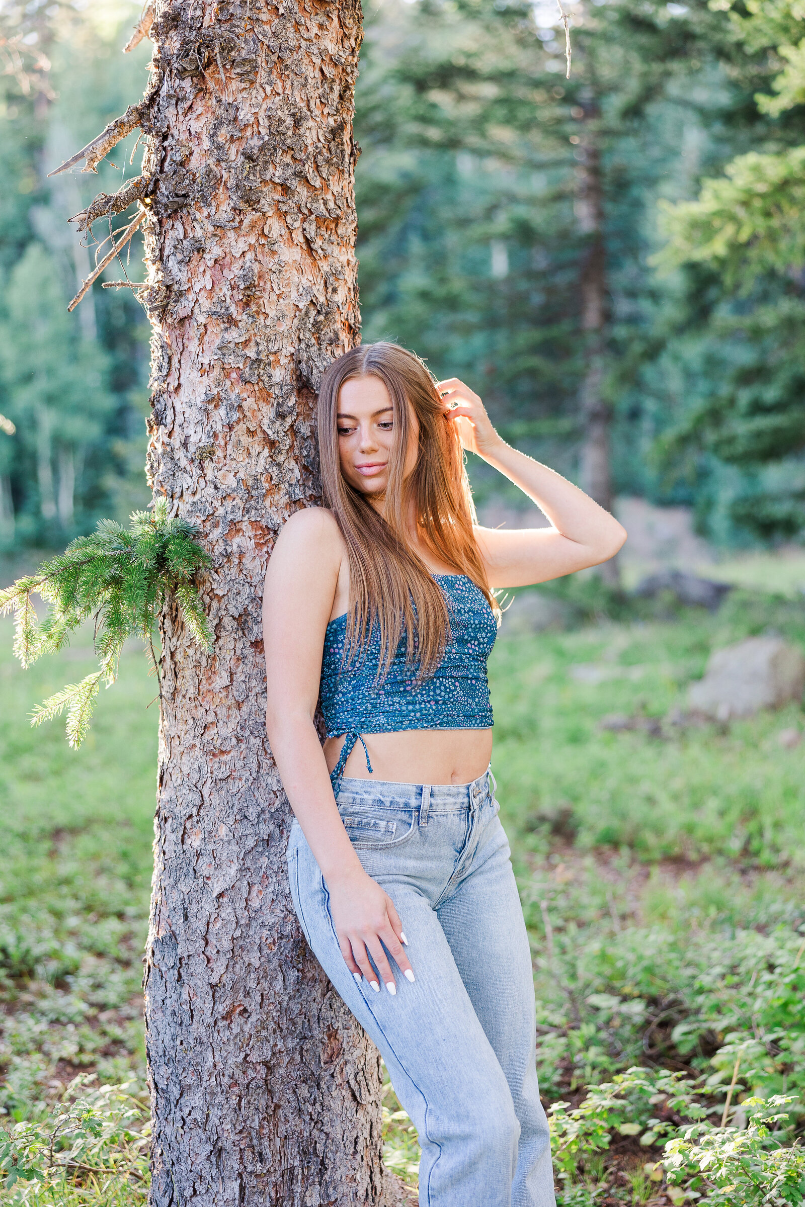 Gorgeous senior stands against a tree in a field in Colorado