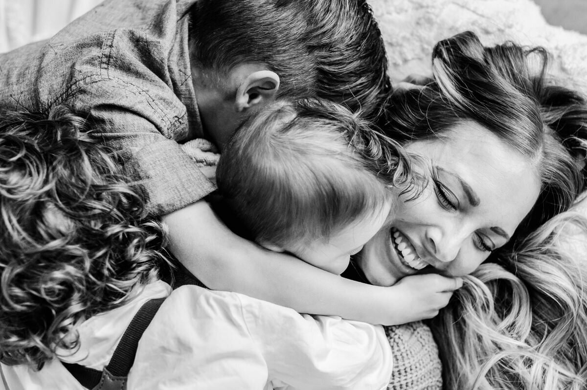 kids hugging mom on bed in Bethesda. MD home