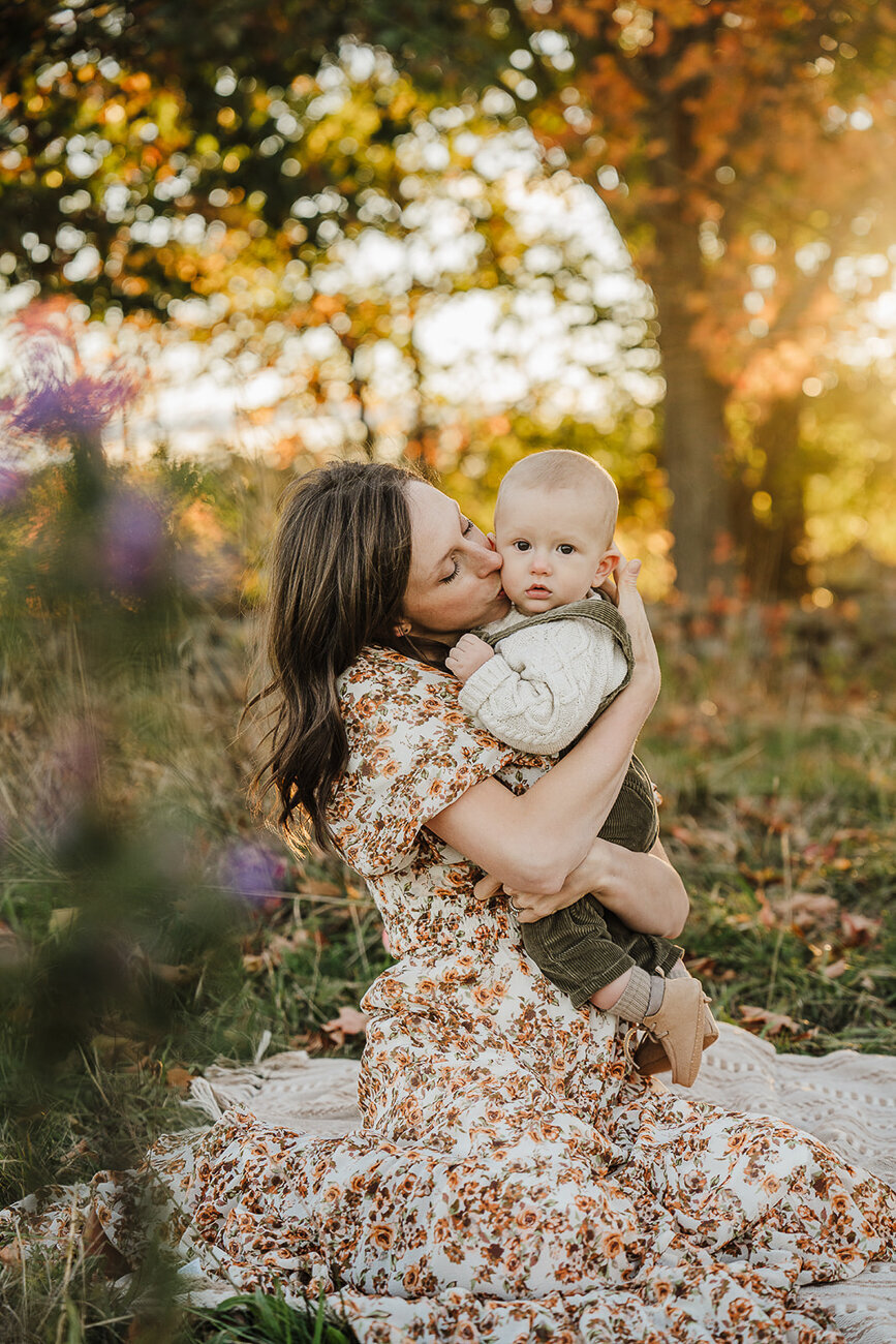 mother holds baby boy close in autumn sunset photoshoot