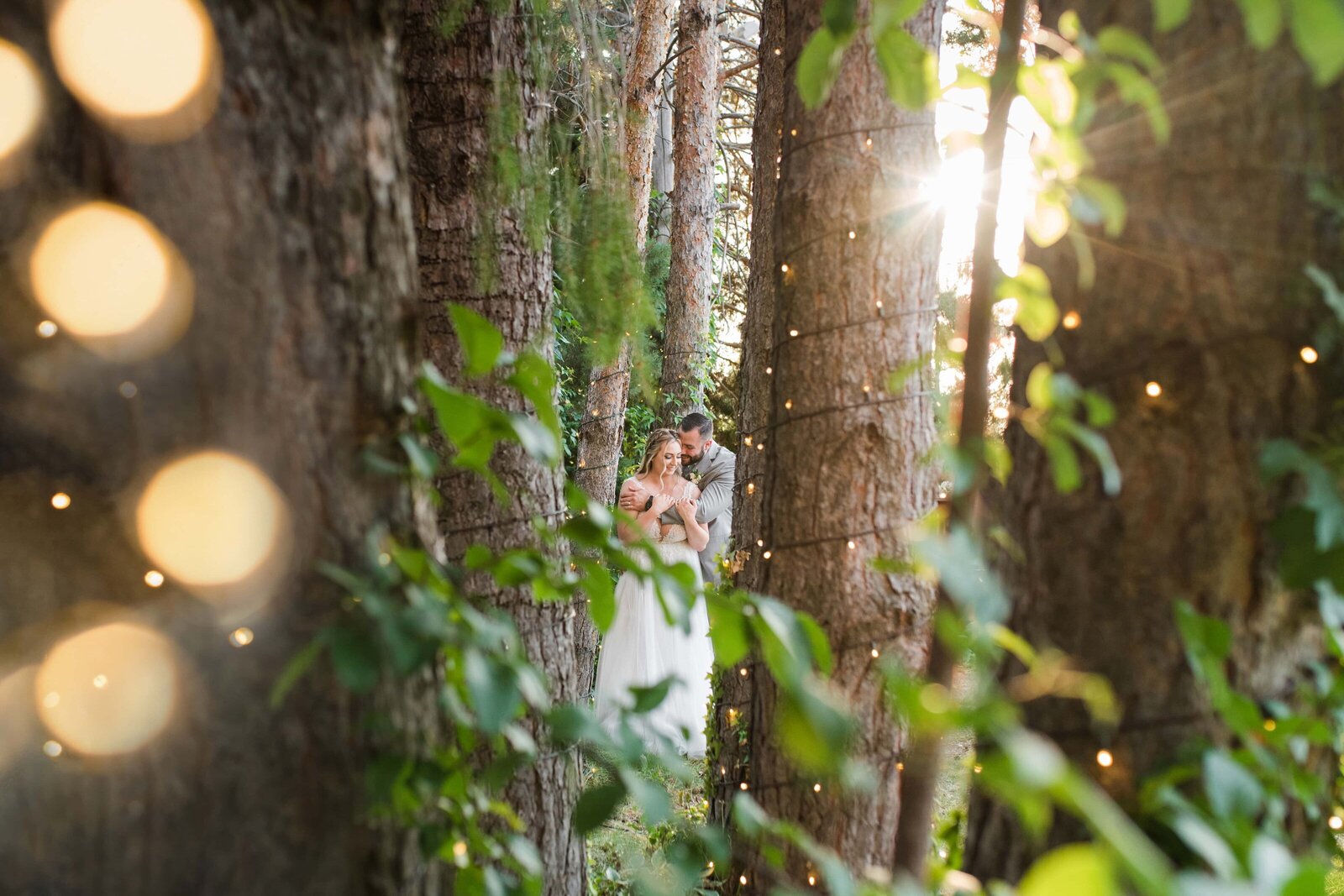 Bride and groom in forested trees with warm sunny backlighting. Oak Hills wedding day.