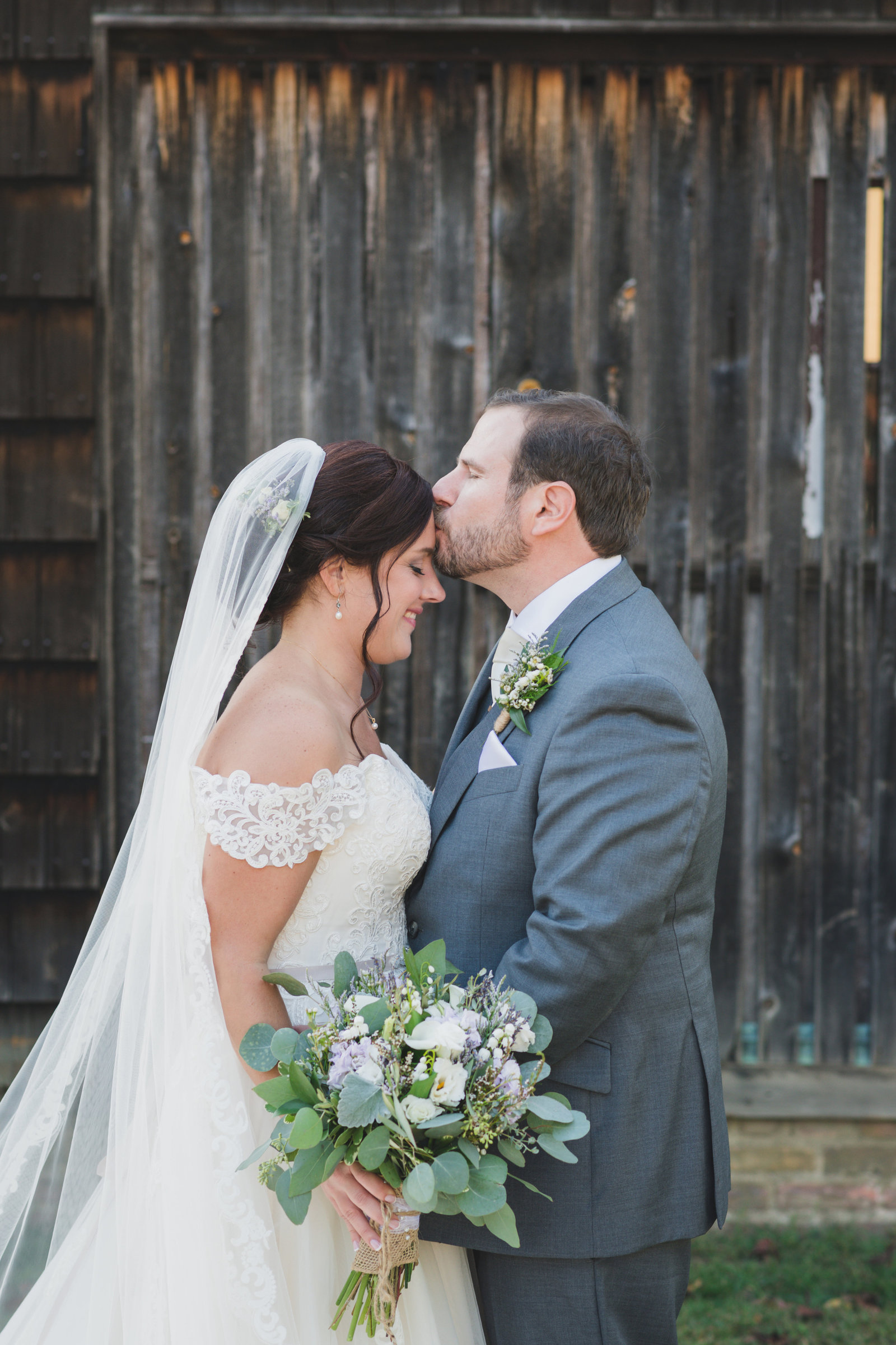 groom kissing brides forehead photo at The Barn at Old Bethpage