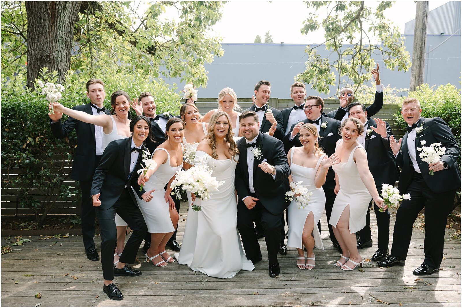 Bridal party posing holding white bouquets out