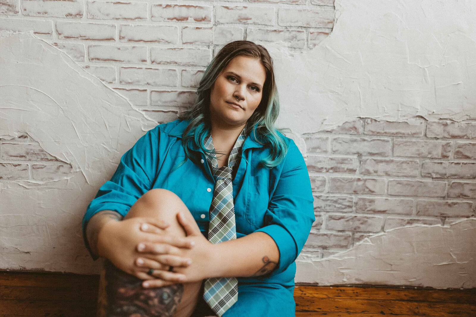woman in a blue suit sitting on the floor and leaning on the wall