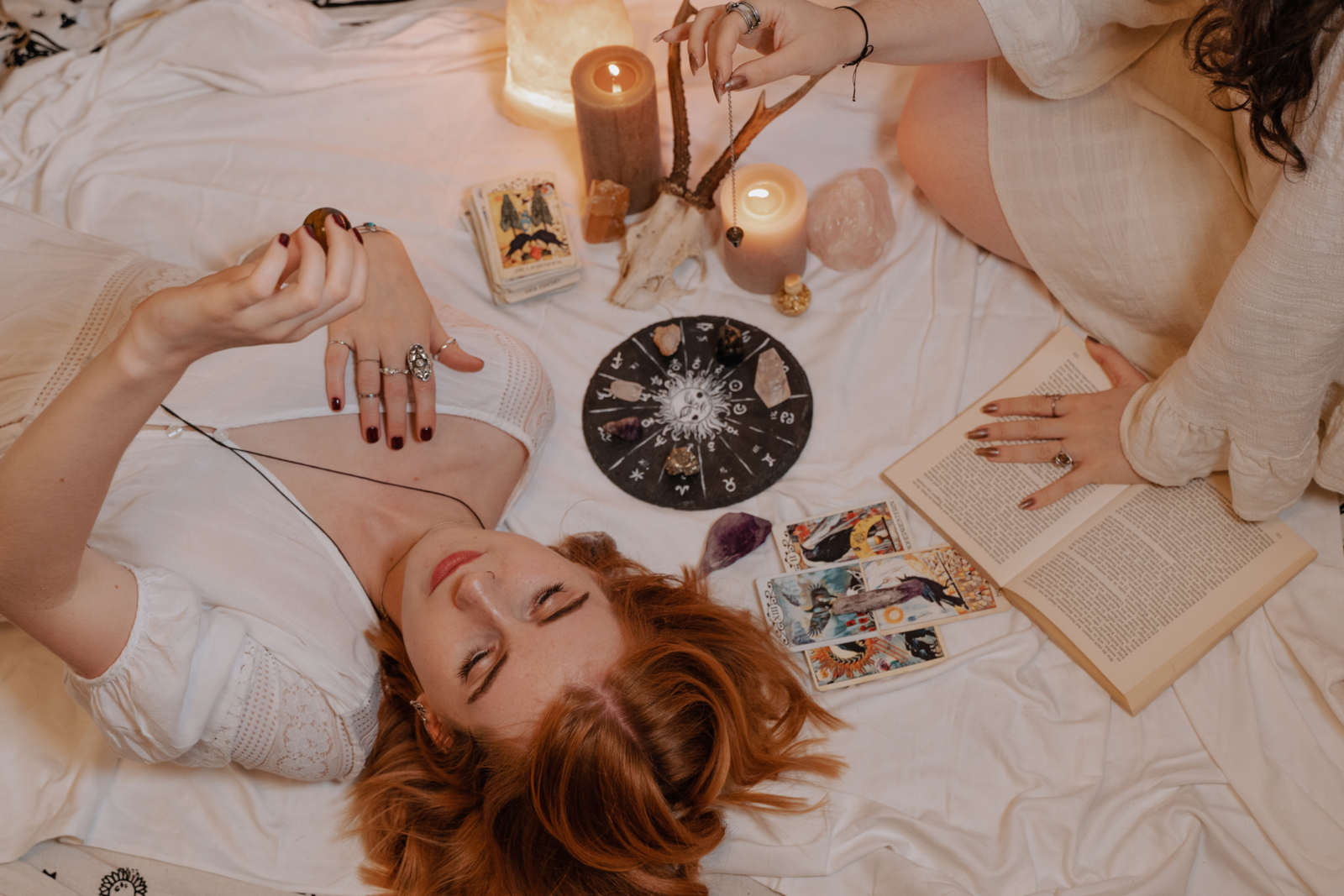 background image of a candle, tarot cards, a pendulum, and two  women