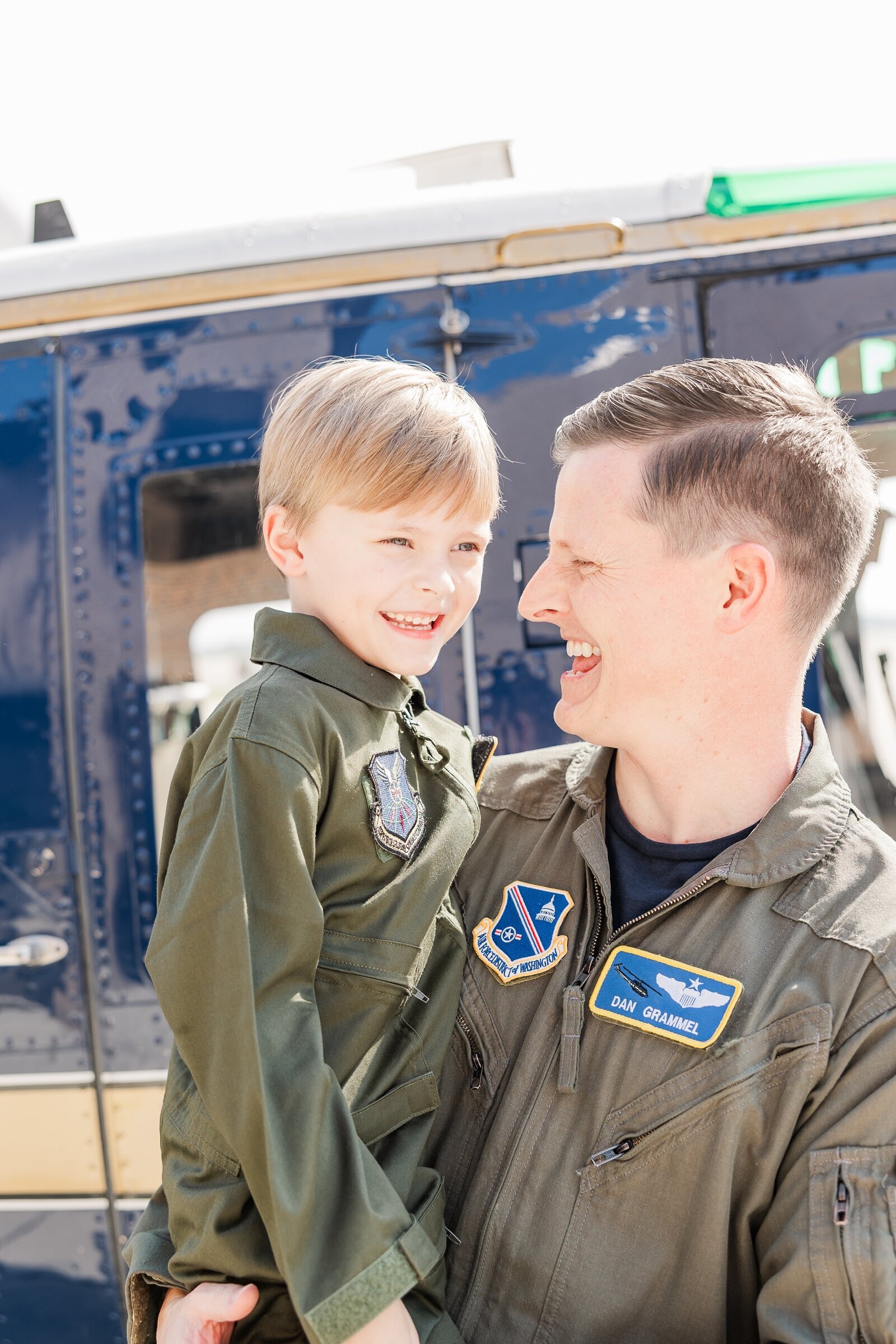 Dad and his son in matching flight suits in front of a helicopter