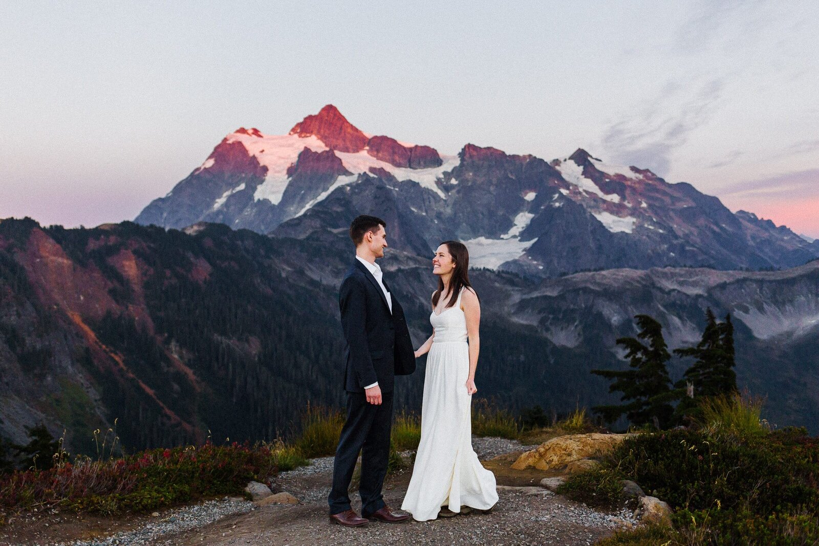 couple laughing with alpenglow on mountains in the background.