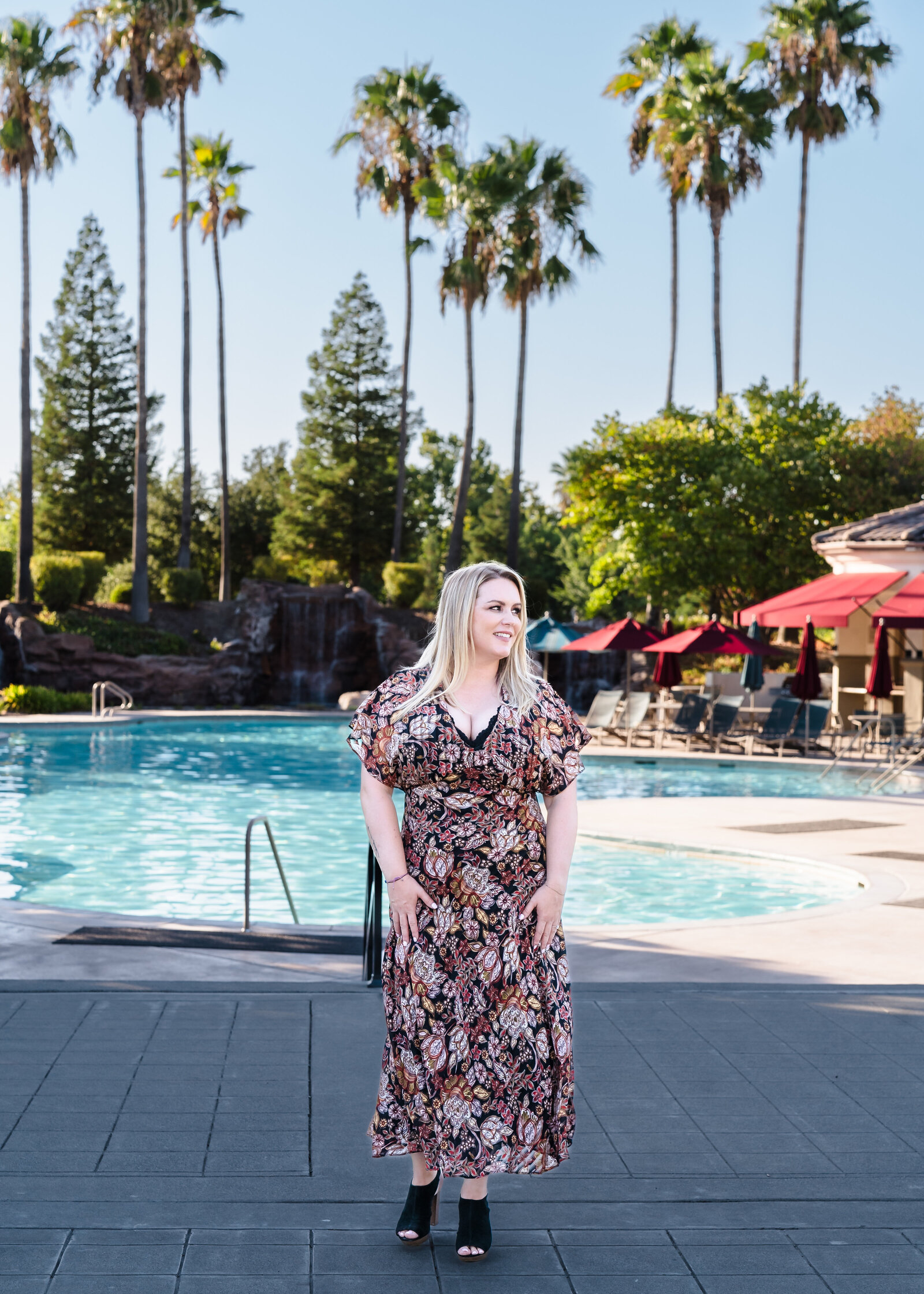 woman stands in a pool area and laughs
