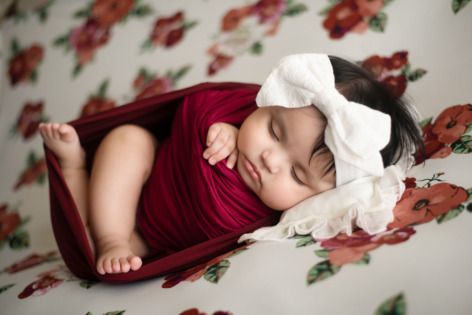 newborn photo on floral backdrop maroon