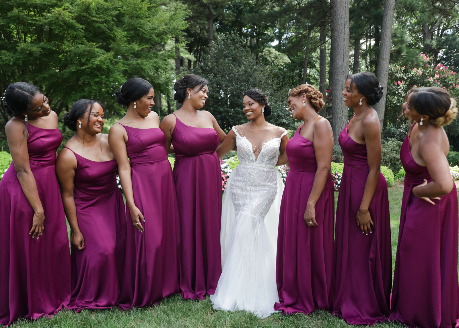 Joyful bridesmaids in burgundy dresses celebrating the bride at a stunning outdoor venue.